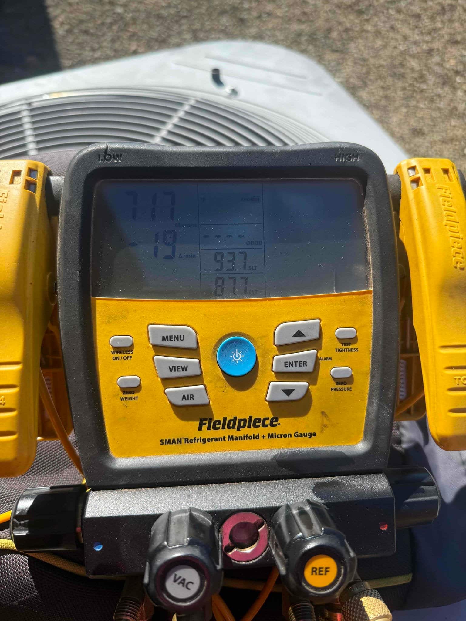 Digital manifold gauge connected to the condenser shows 93.7 psi on the high-side port during system charging.