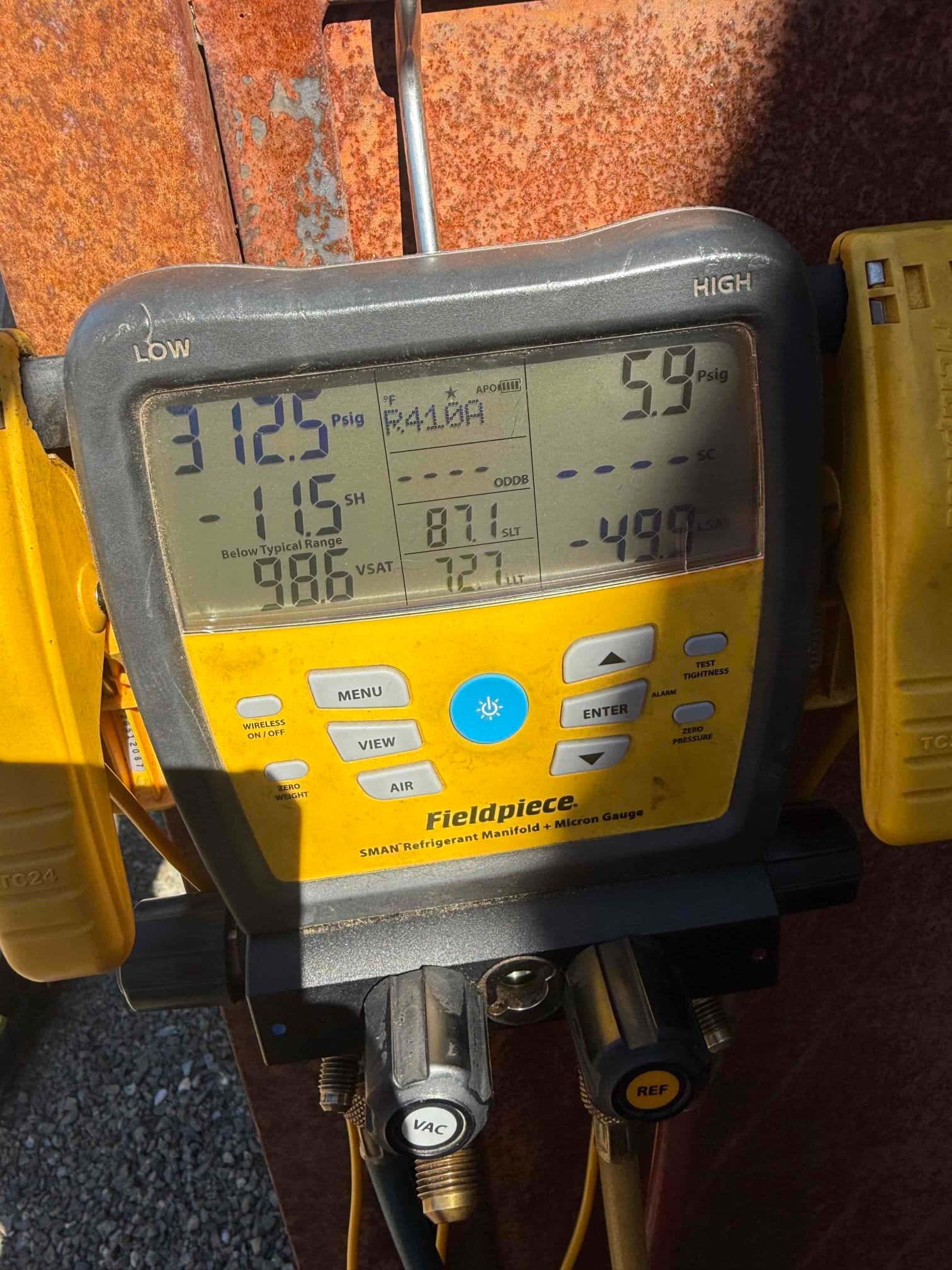 Digital manifold gauge on an outdoor unit shows 312.5 psi high-side and 59.0 psi low-side pressures with refrigerant R410A selected.