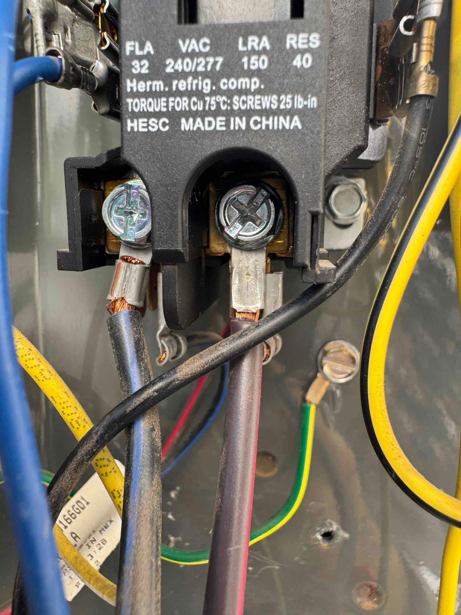 Close-up of an HVAC contactor with connected line and load wires, showing clean terminals and intact insulation inside the condenser unit.