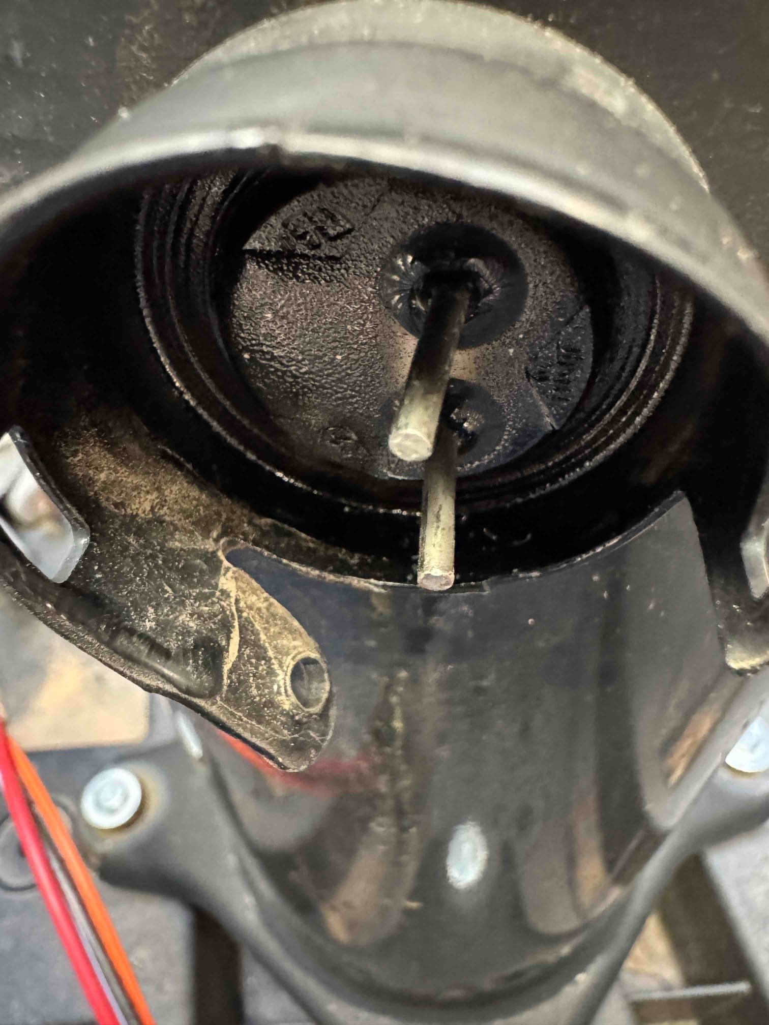 Close-up of a thermostat wall base with exposed mounting tube and two protruding electrical leads, ready for wiring.