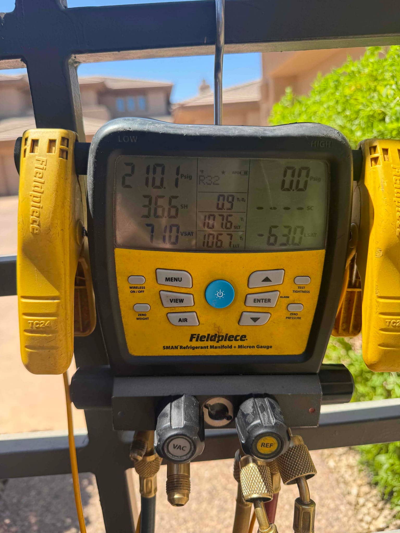 Digital manifold gauges show operating pressures with temperature clamps attached during commissioning of the new mini-split system.