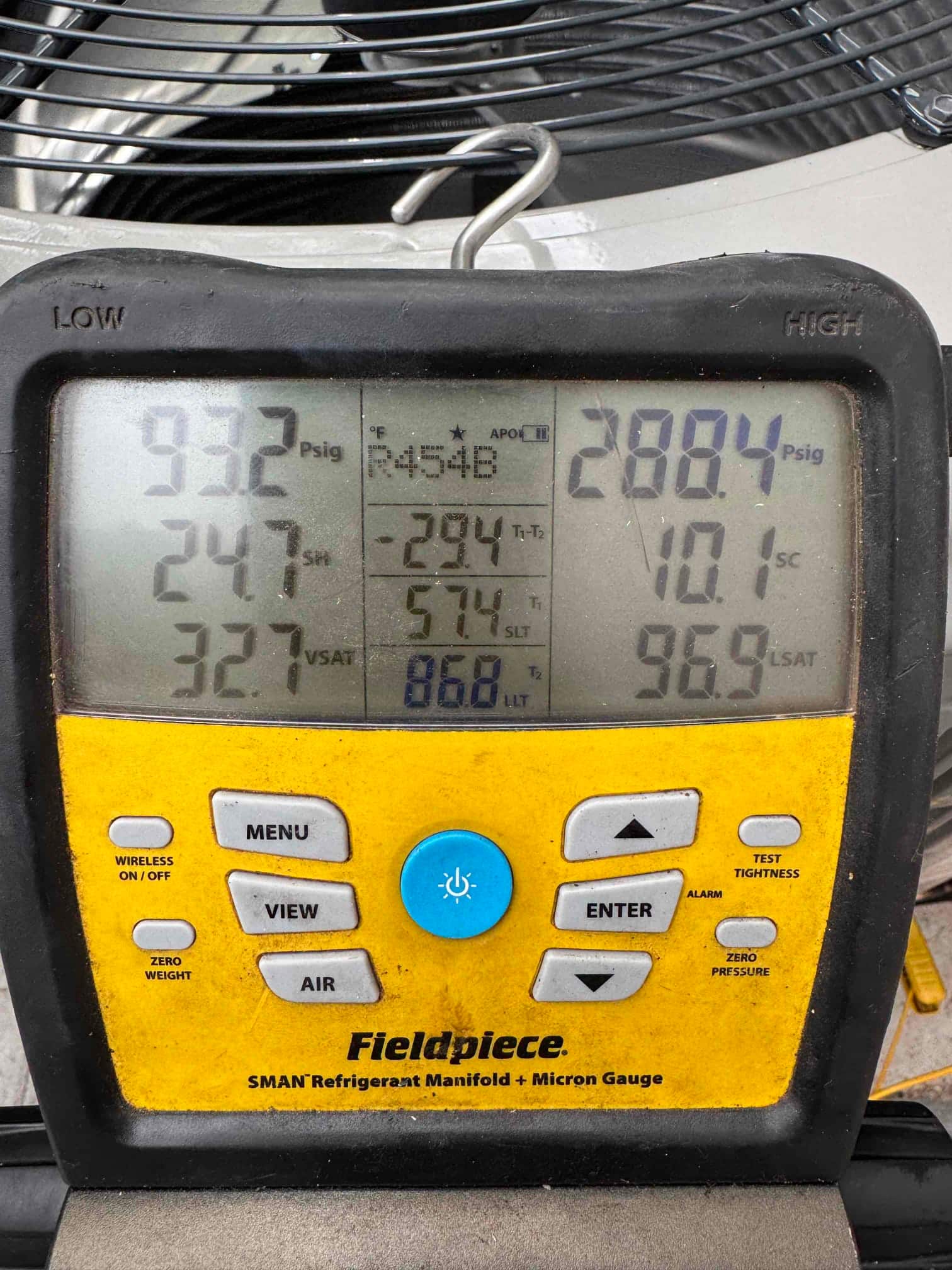 Digital manifold shows operating pressures with refrigerant type R-454B during commissioning of the outdoor condenser.