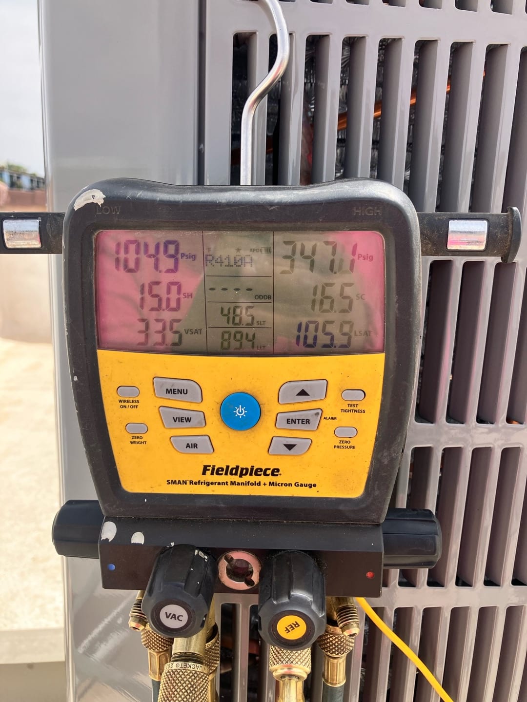 Digital manifold shows system operating pressures with low side at 104.9 PSI and high side at 347.1 PSI on the outdoor unit.