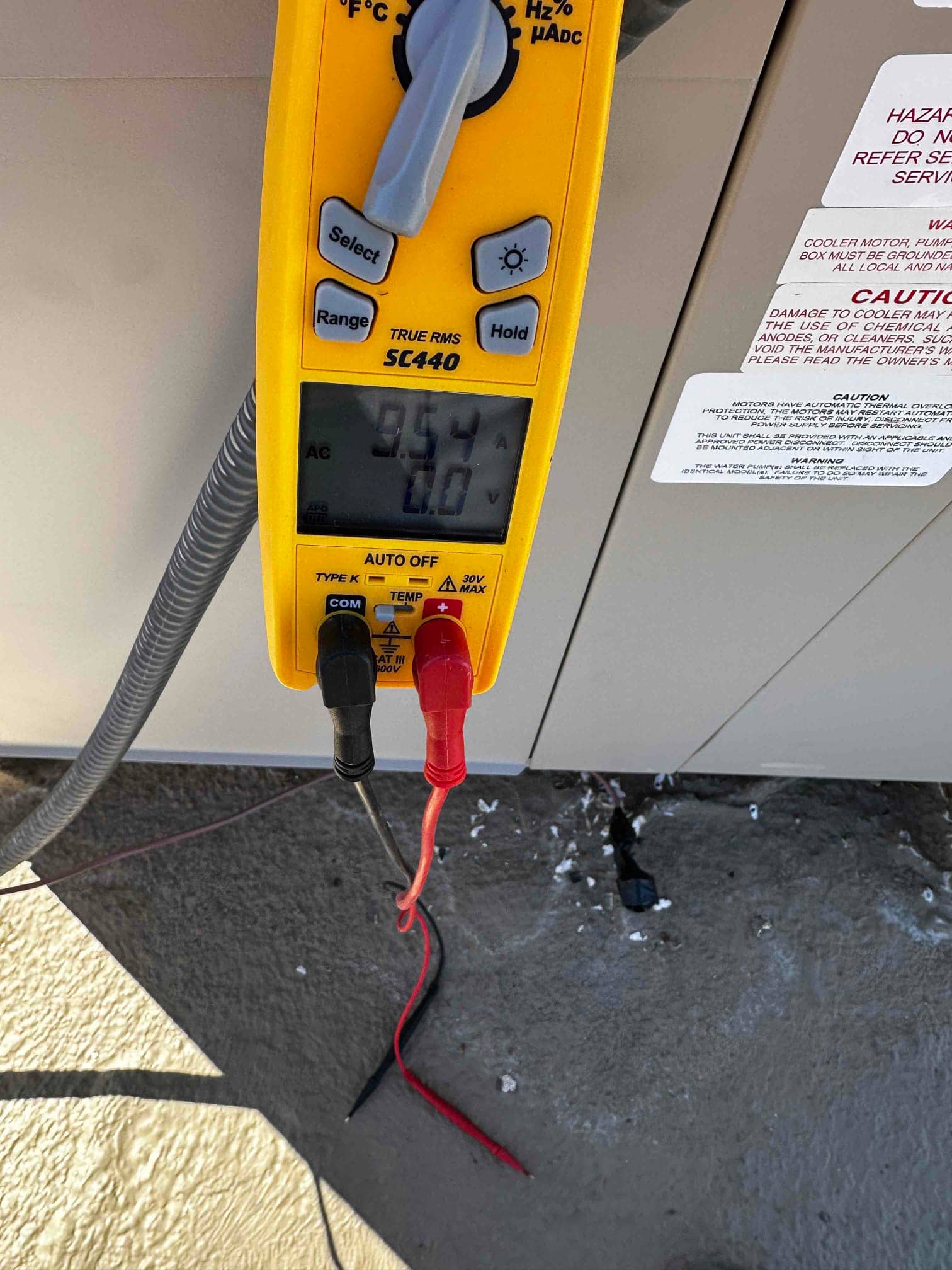 Digital multimeter set to measure AC current shows 9.54 amps while testing the newly installed HVAC equipment.