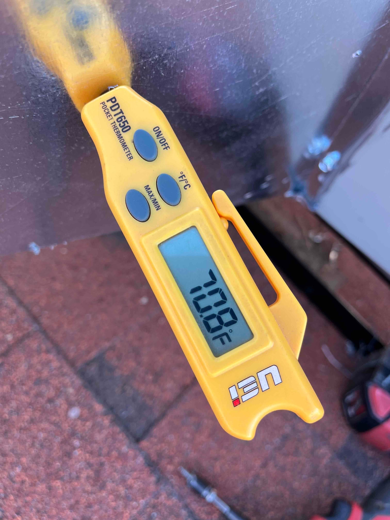 Digital pocket thermometer displays 70.8°F while measuring air temperature at the HVAC installation site.