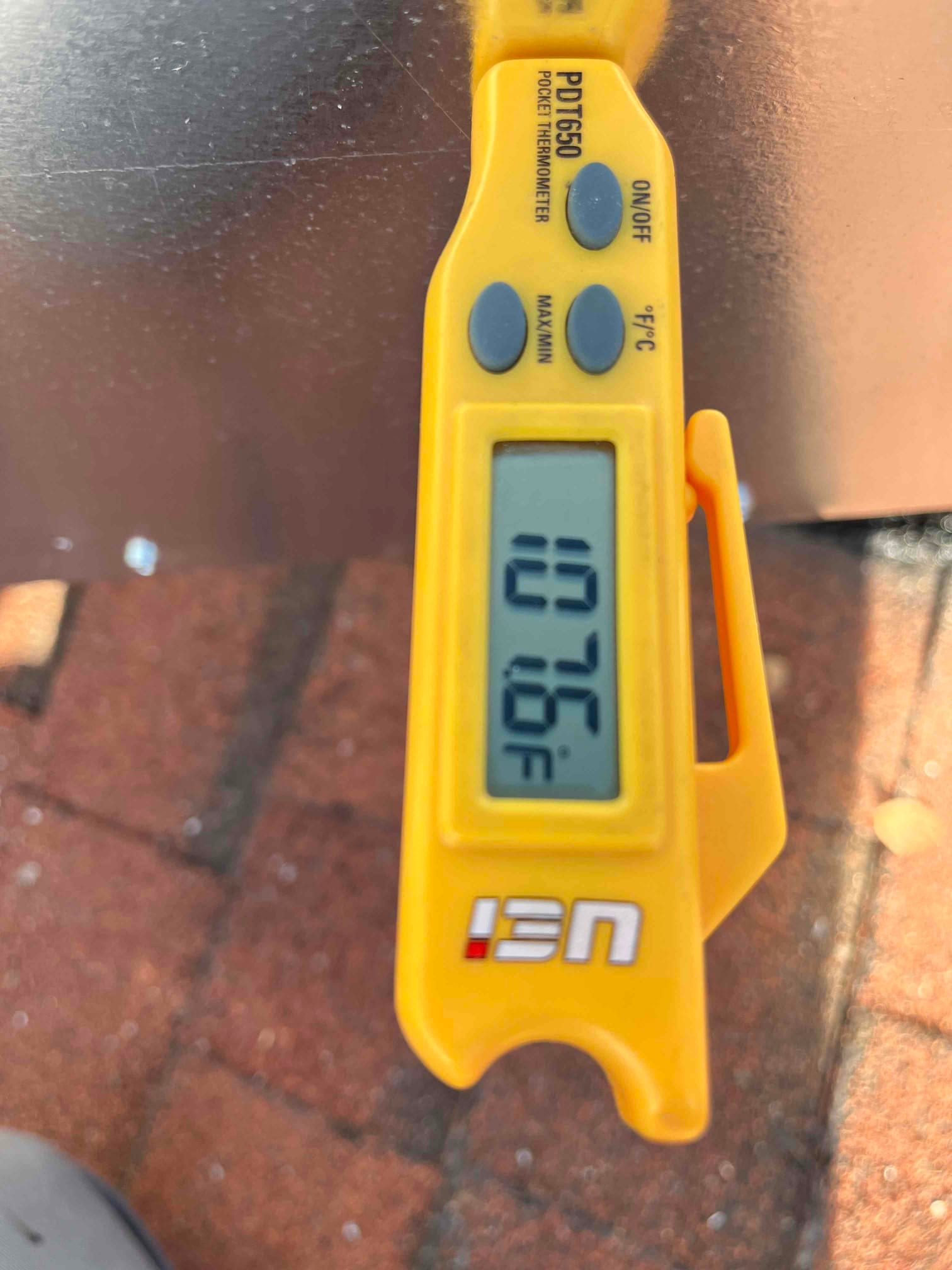 Digital pocket thermometer displays 76°F, documenting return air temperature during HVAC commissioning.