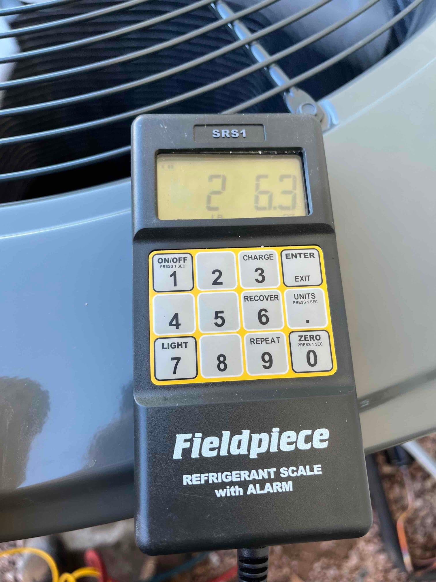 Digital refrigerant scale on top of the outdoor condenser shows 2.63 pounds during charging of the new heat pump system.
