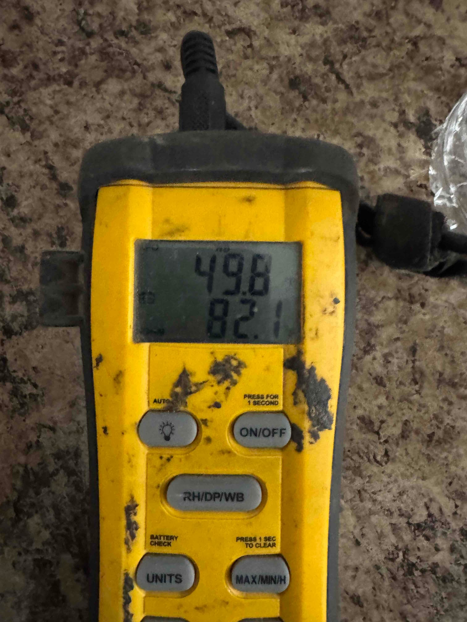 Digital thermometer displays 49.8 degrees Fahrenheit, documenting cold supply air temperature during cooling operation.