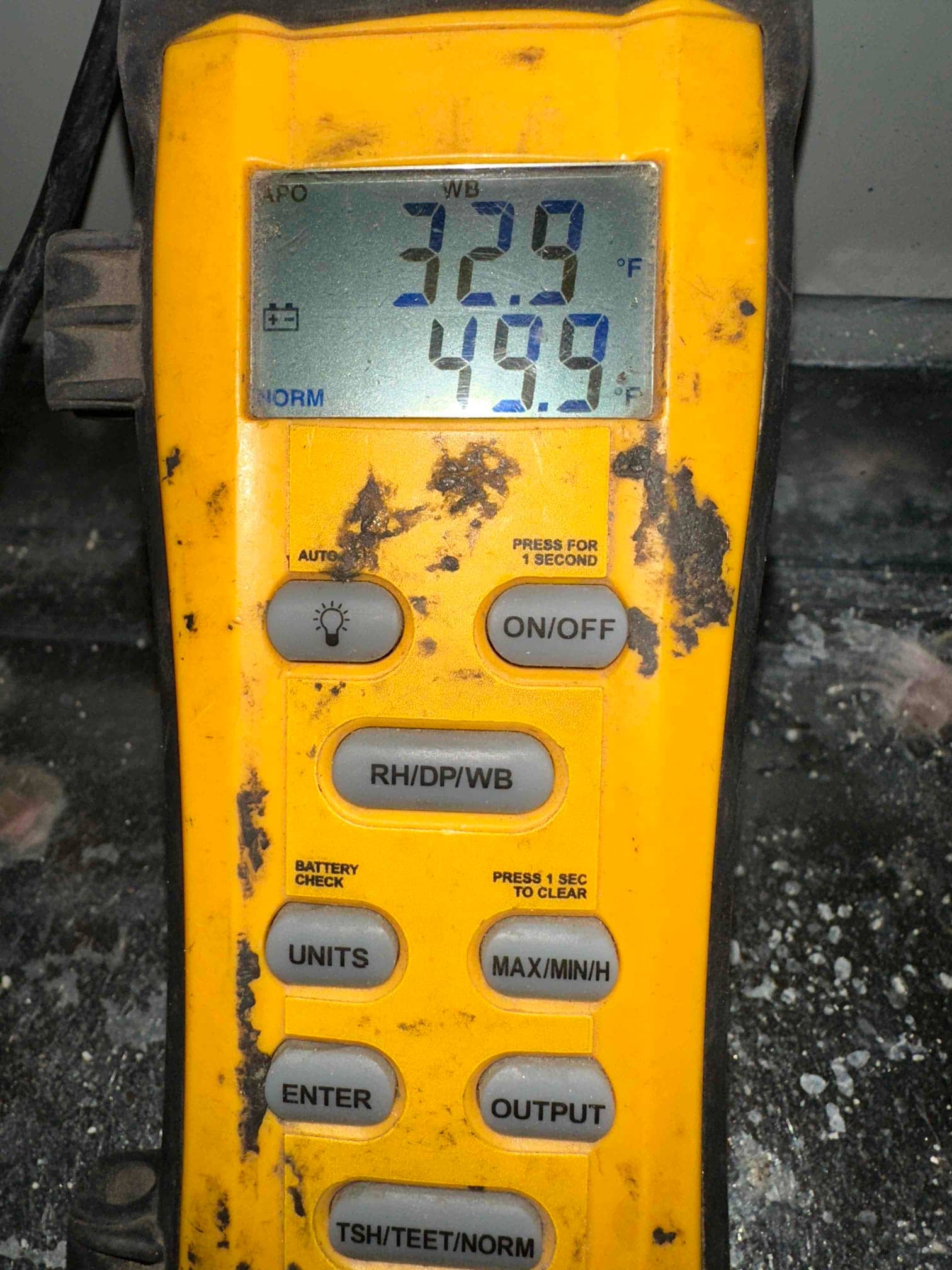 Digital thermometer displays 49.9 degrees Fahrenheit, documenting cold supply air during system commissioning.