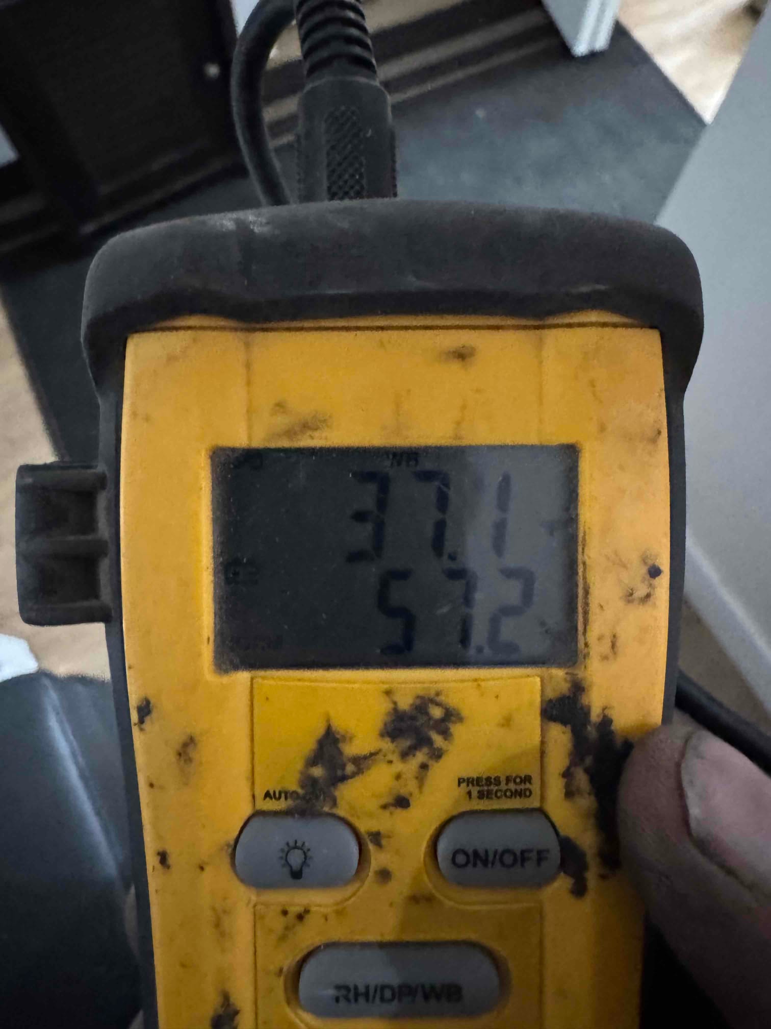 Digital thermometer displays 57.2 degrees Fahrenheit, documenting supply air temperature during system commissioning.