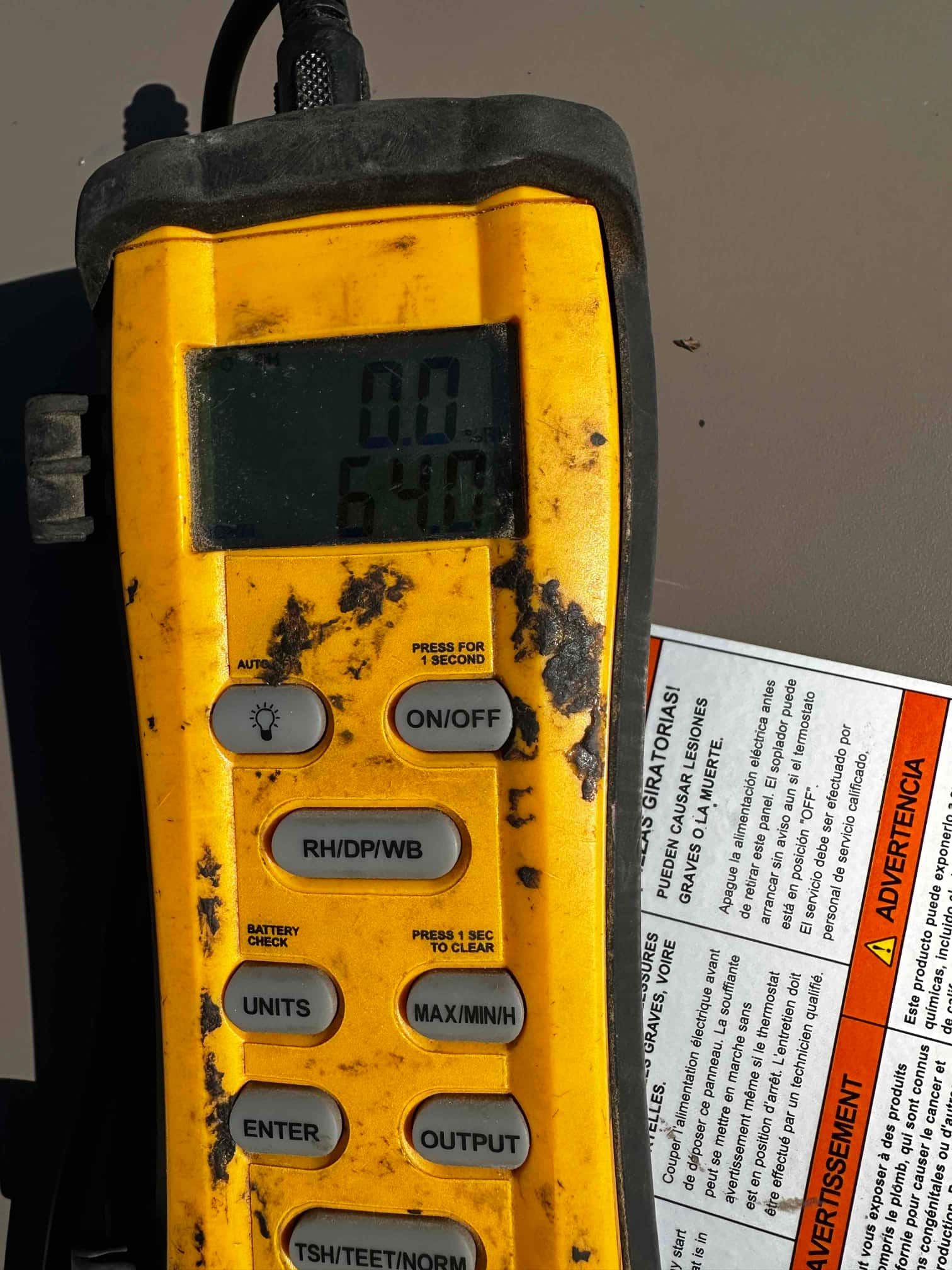 Digital thermometer displays 64.0 degrees Fahrenheit during air temperature measurement at the HVAC system.