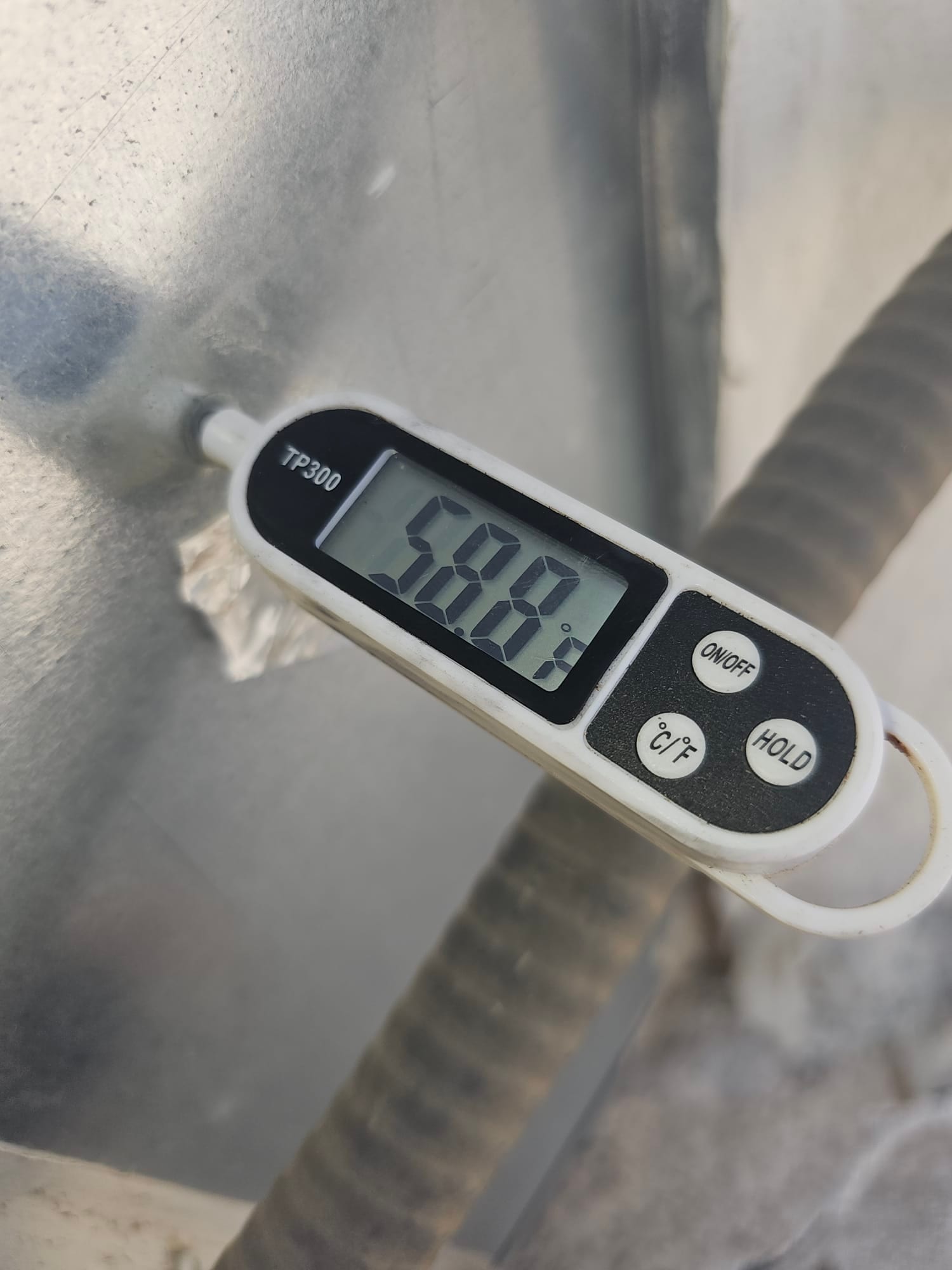 Digital thermometer probe shows 58.8 °F on a metal surface near insulated refrigerant lines.