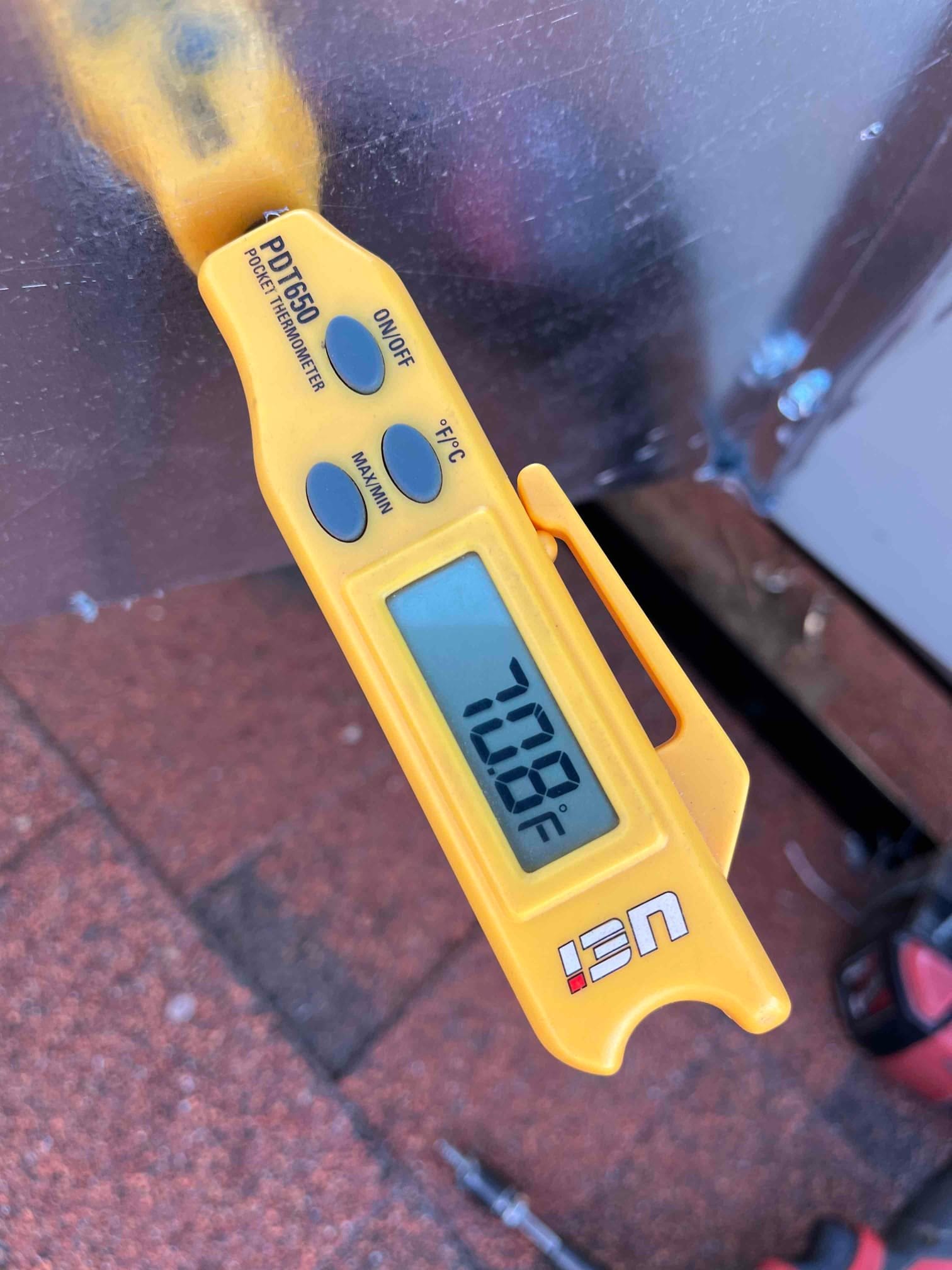 Digital thermometer probe shows 70.8°F, documenting return air temperature during commissioning of the HVAC system.