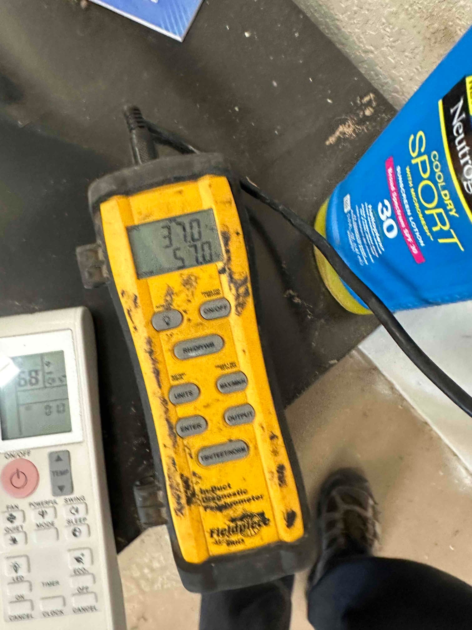 Digital thermometer shows a 57.0°F reading during supply air temperature check after mini-split installation.