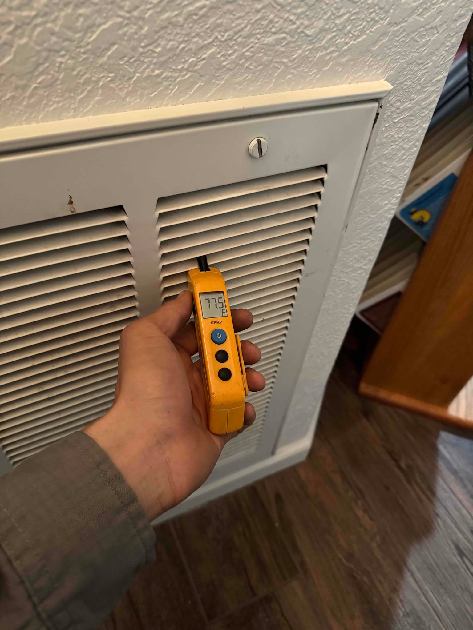 Digital thermometer shows 77.5 °F at the return air grille during system operation.
