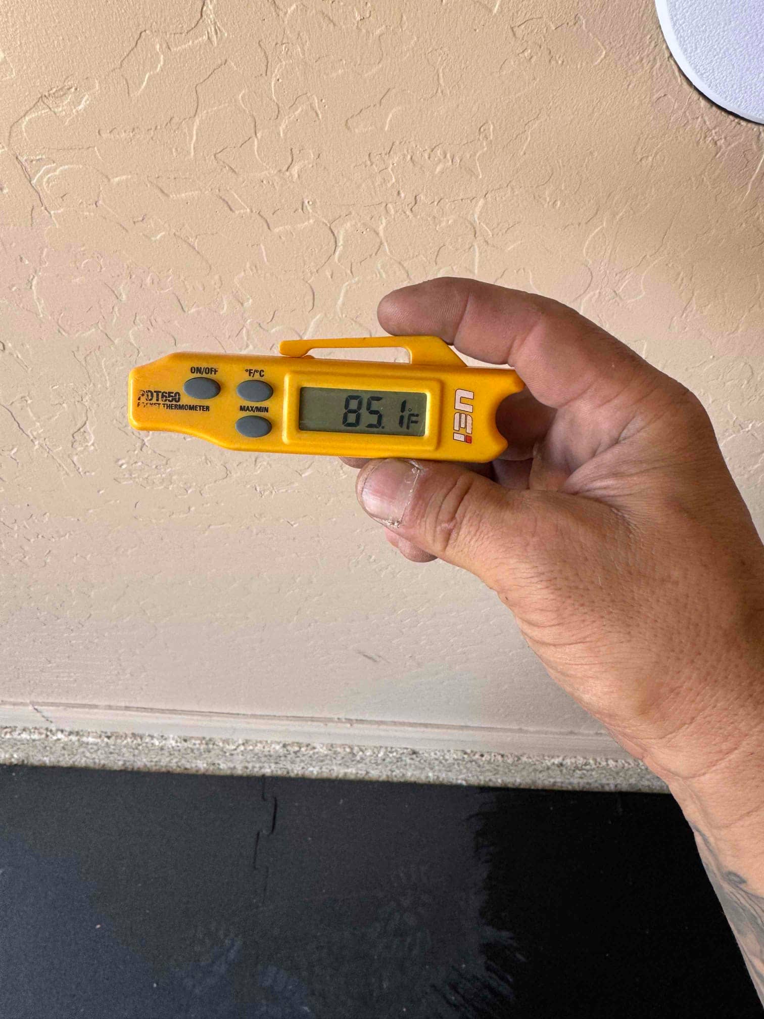 Digital thermometer shows 85.1°F while checking air temperature during HVAC commissioning.