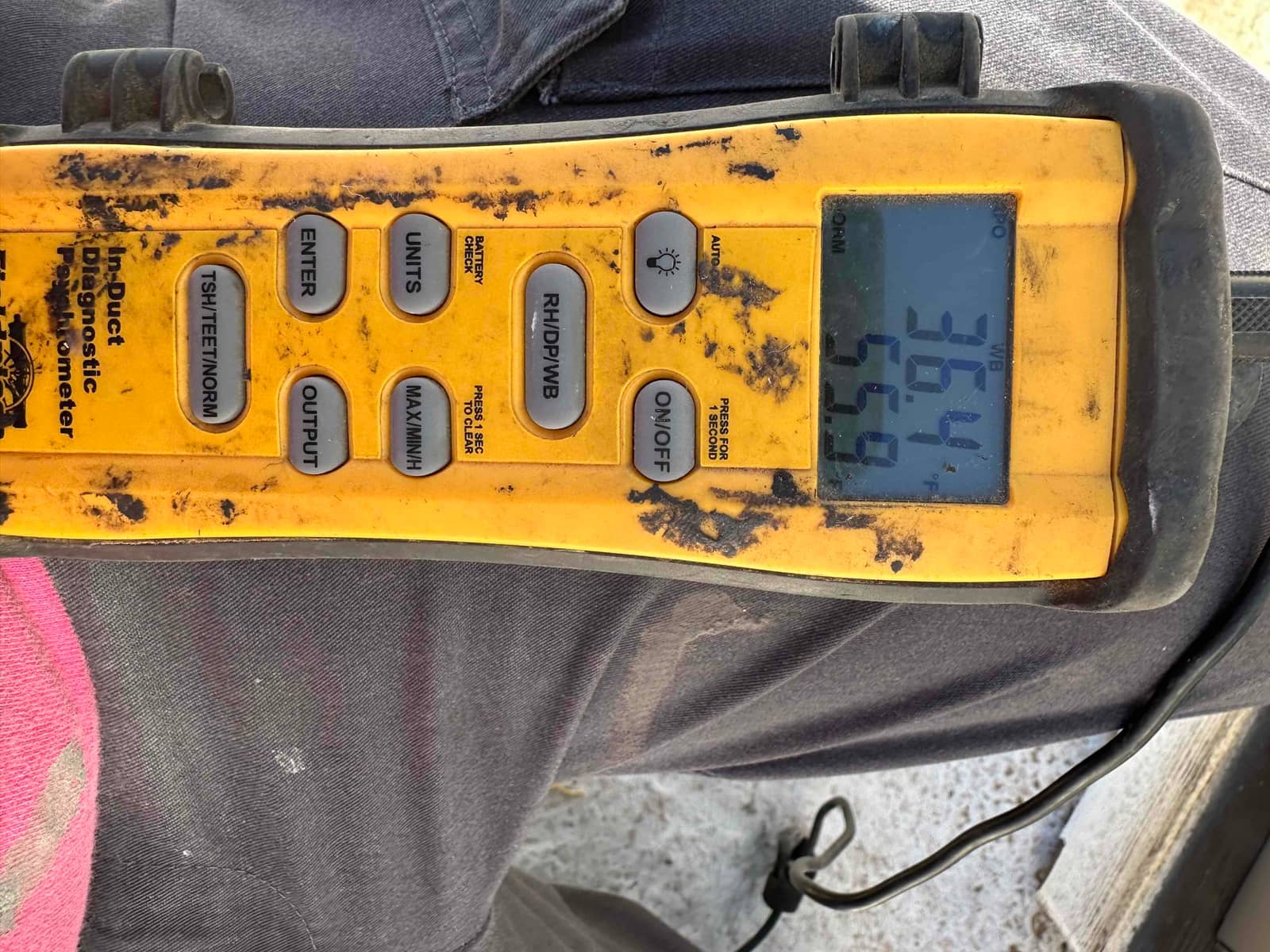 Digital thermometer shows air temperature readings during commissioning, with the probe connected and display indicating values in degrees Fahrenheit.