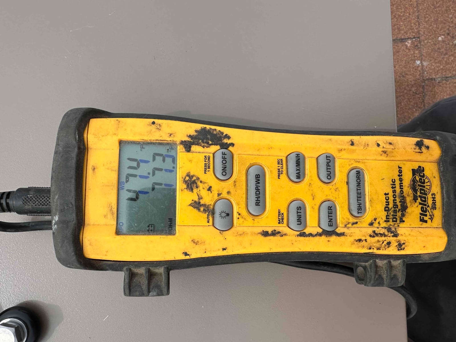 Digital thermometer shows a duct temperature reading of 71.3 degrees Fahrenheit during air-side commissioning of the new system.