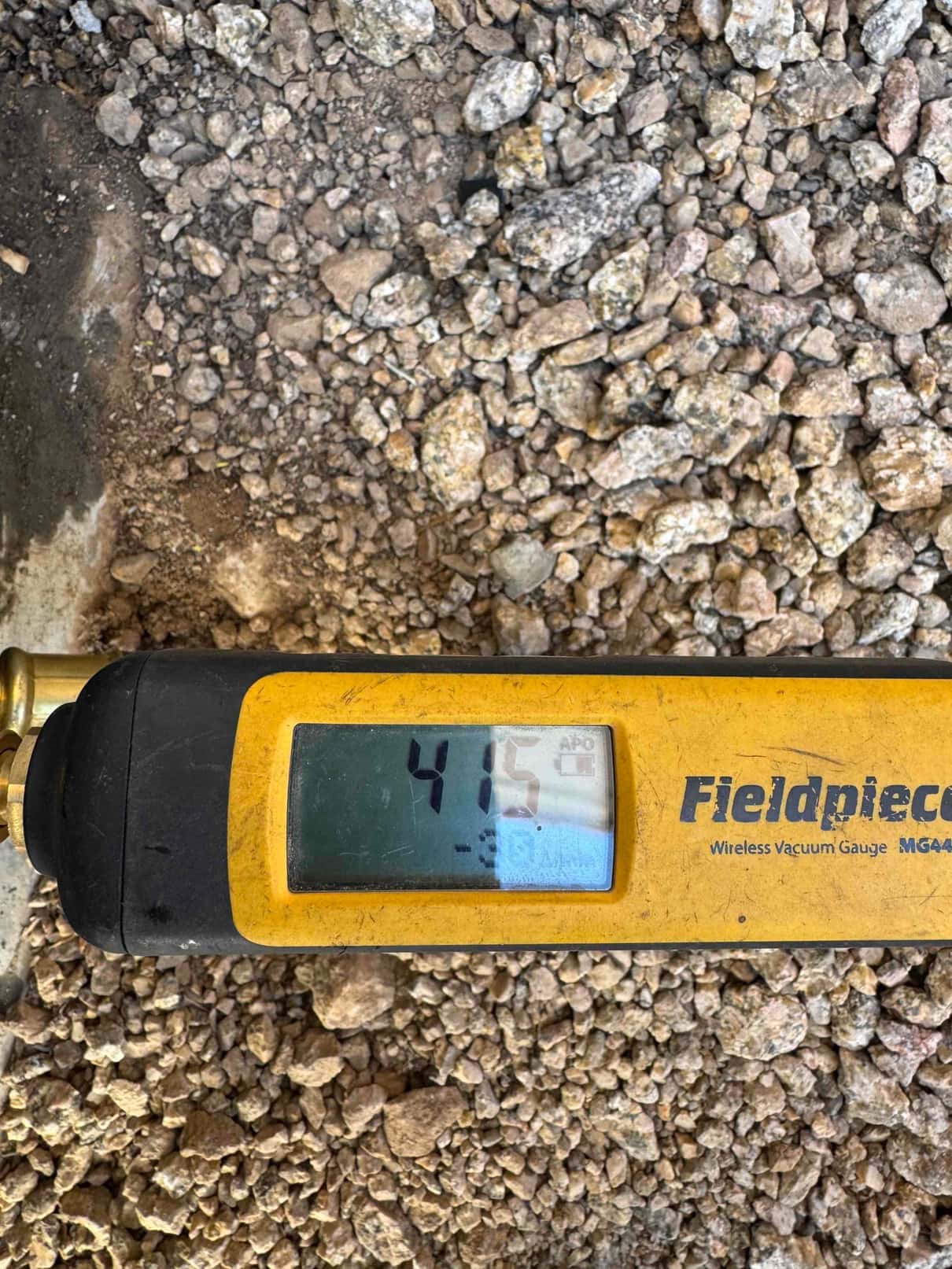 Digital vacuum gauge reads 415 microns during evacuation, confirming a deep vacuum before releasing refrigerant into the system.