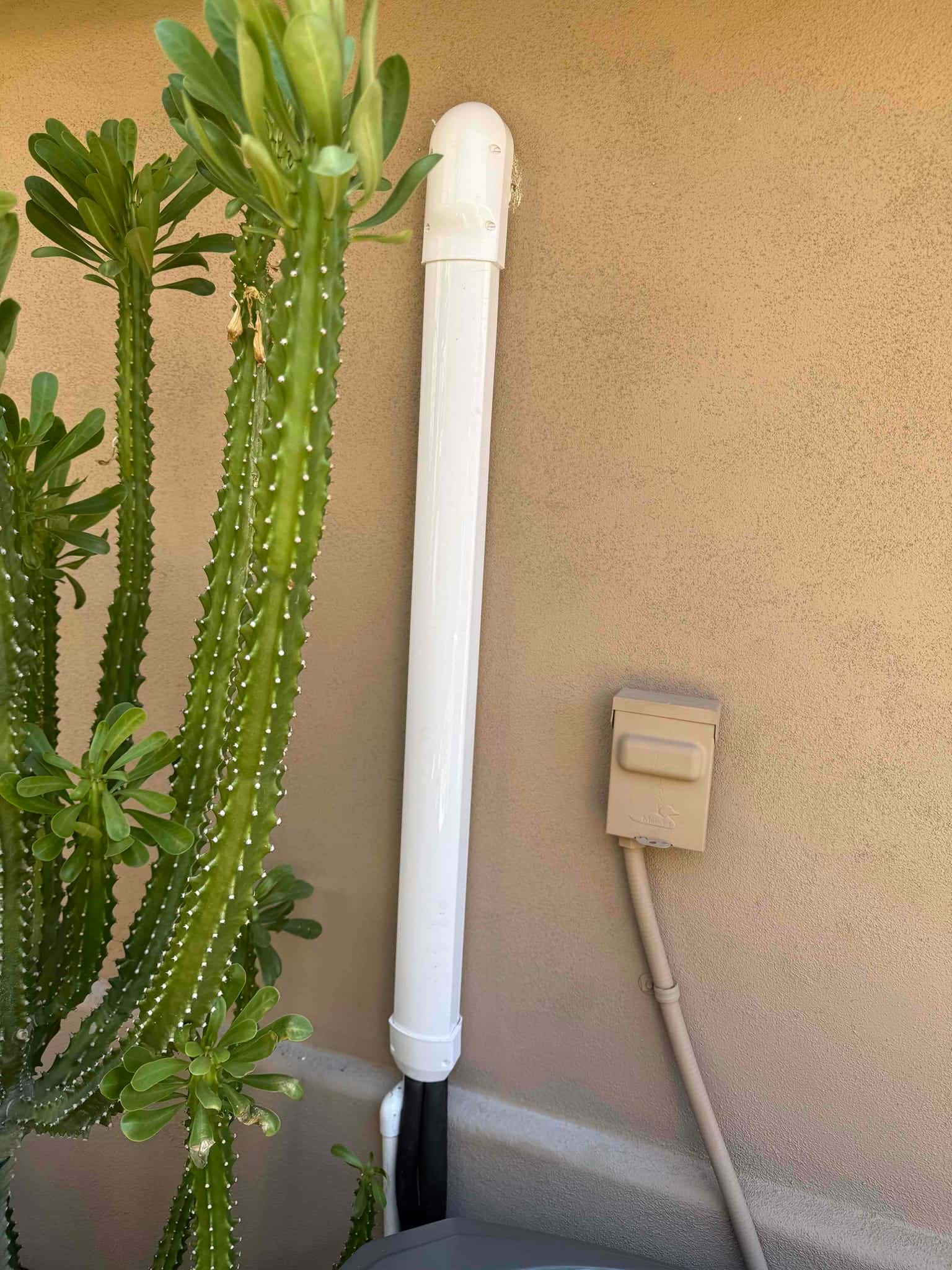 Exterior installation shows a covered line set with termination elbow and a mounted weatherproof electrical disconnect beside the condenser.