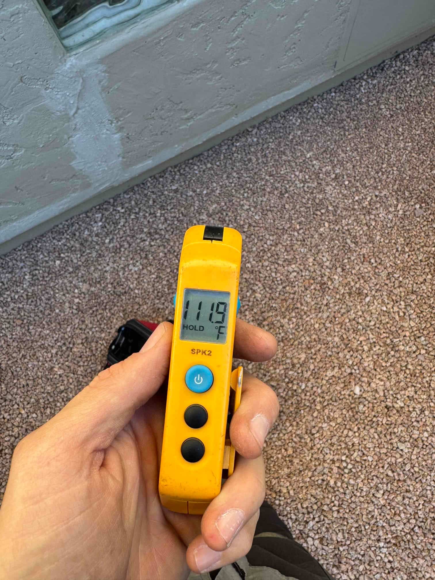 Handheld digital thermometer shows 111.9 °F on the display with the hold function engaged.