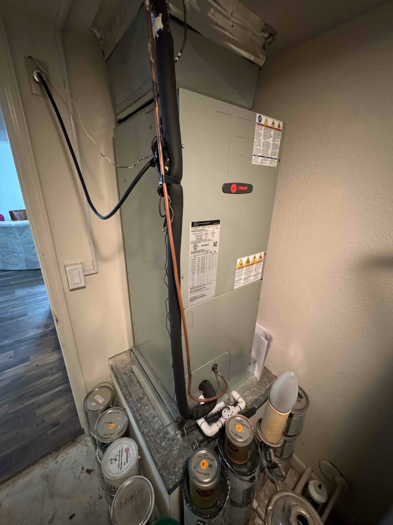 Indoor air handler with insulated refrigerant line, condensate drain piping, and service panel accessible in a closet installation.