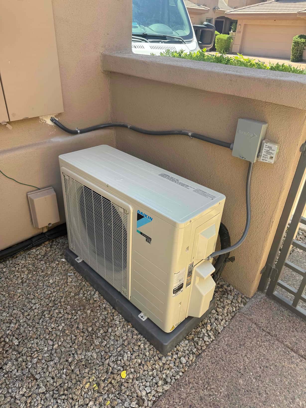 New mini-split outdoor unit set on a level pad with insulated line set and mounted electrical disconnect.