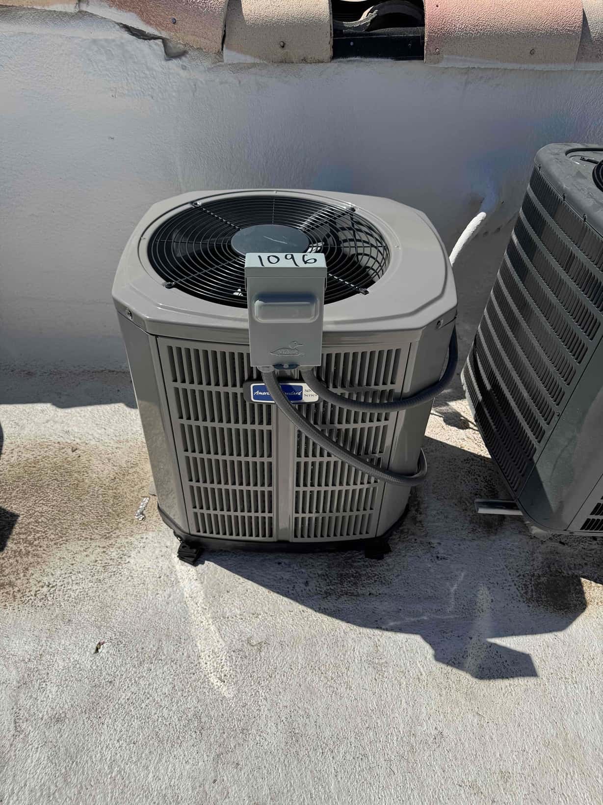 New outdoor condenser set on a roof with flexible electrical whip connected and disconnect box mounted beside the unit.