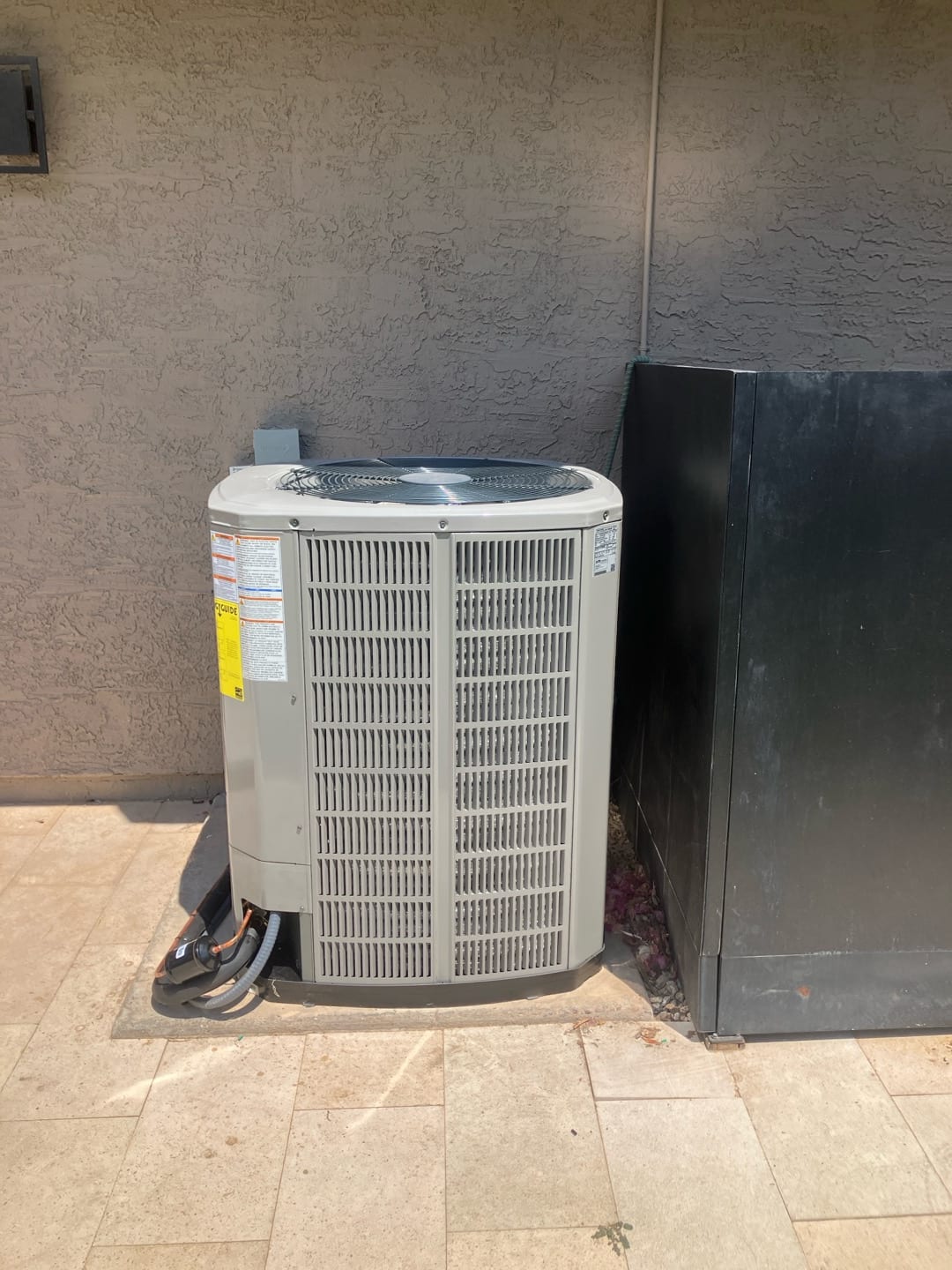 New outdoor heat pump condenser set on a level pad with insulated refrigerant lines and electrical whip connected.