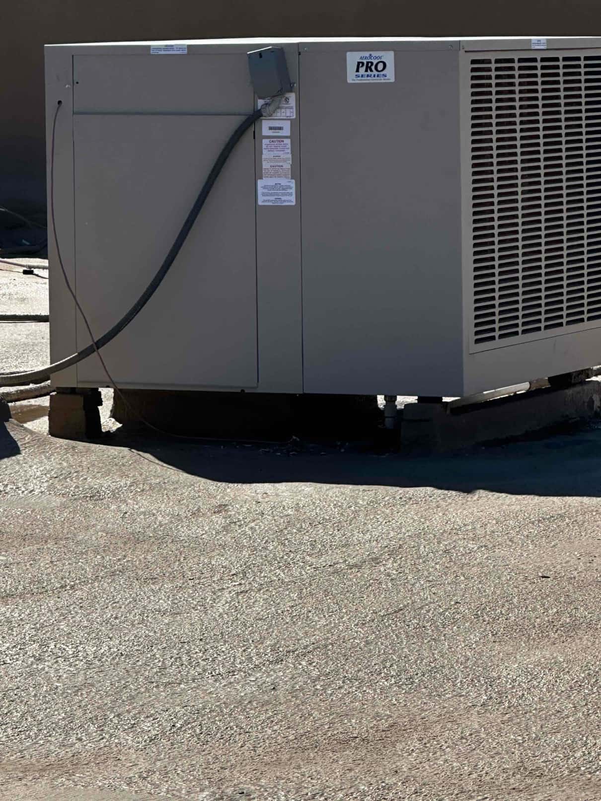 New rooftop evaporative cooler installed on curb with electrical whip connected and exterior service access panels closed.