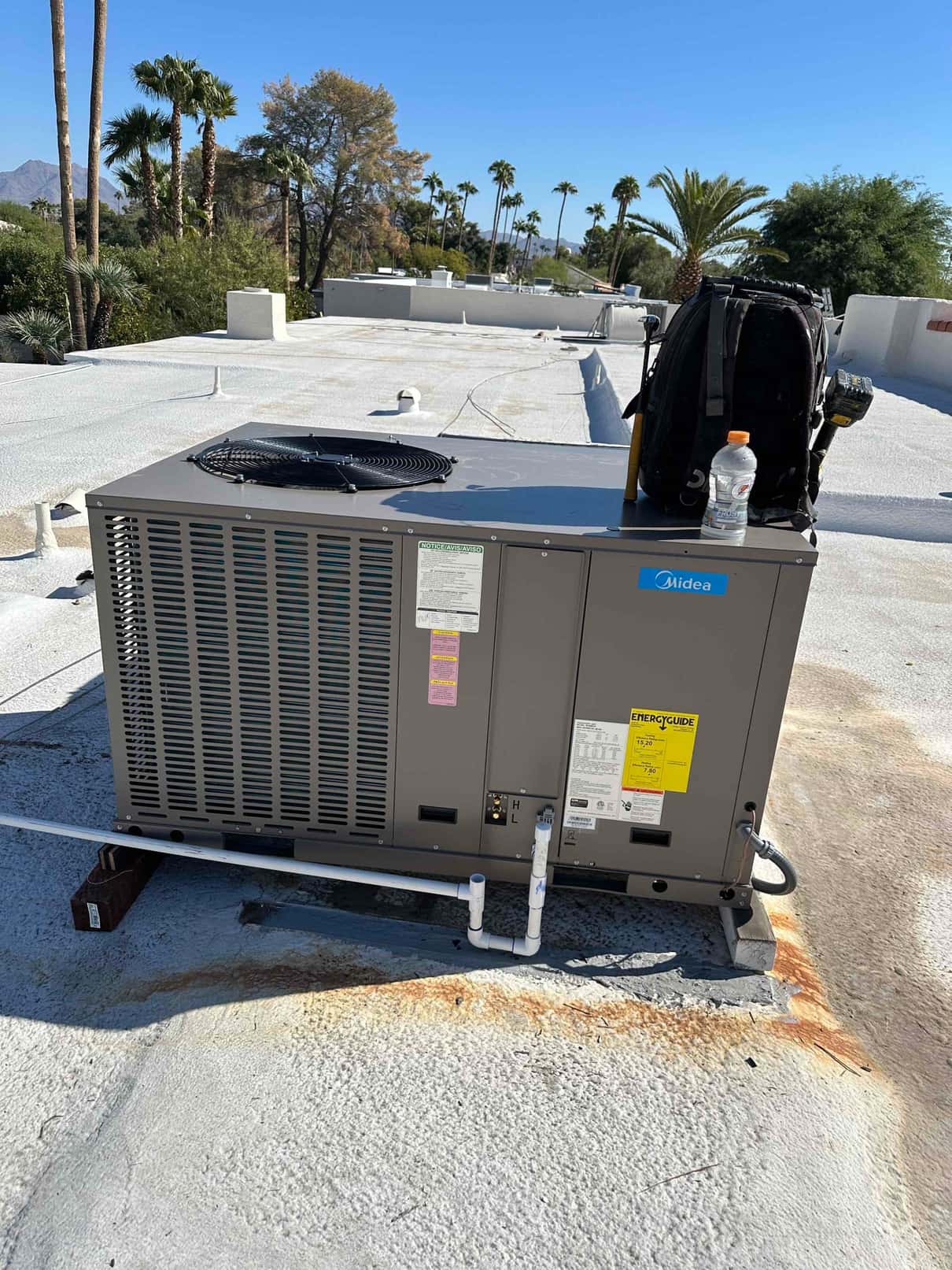 New rooftop package HVAC unit installed on a curb with condensate drain piping connected and electrical whip routed to the cabinet.