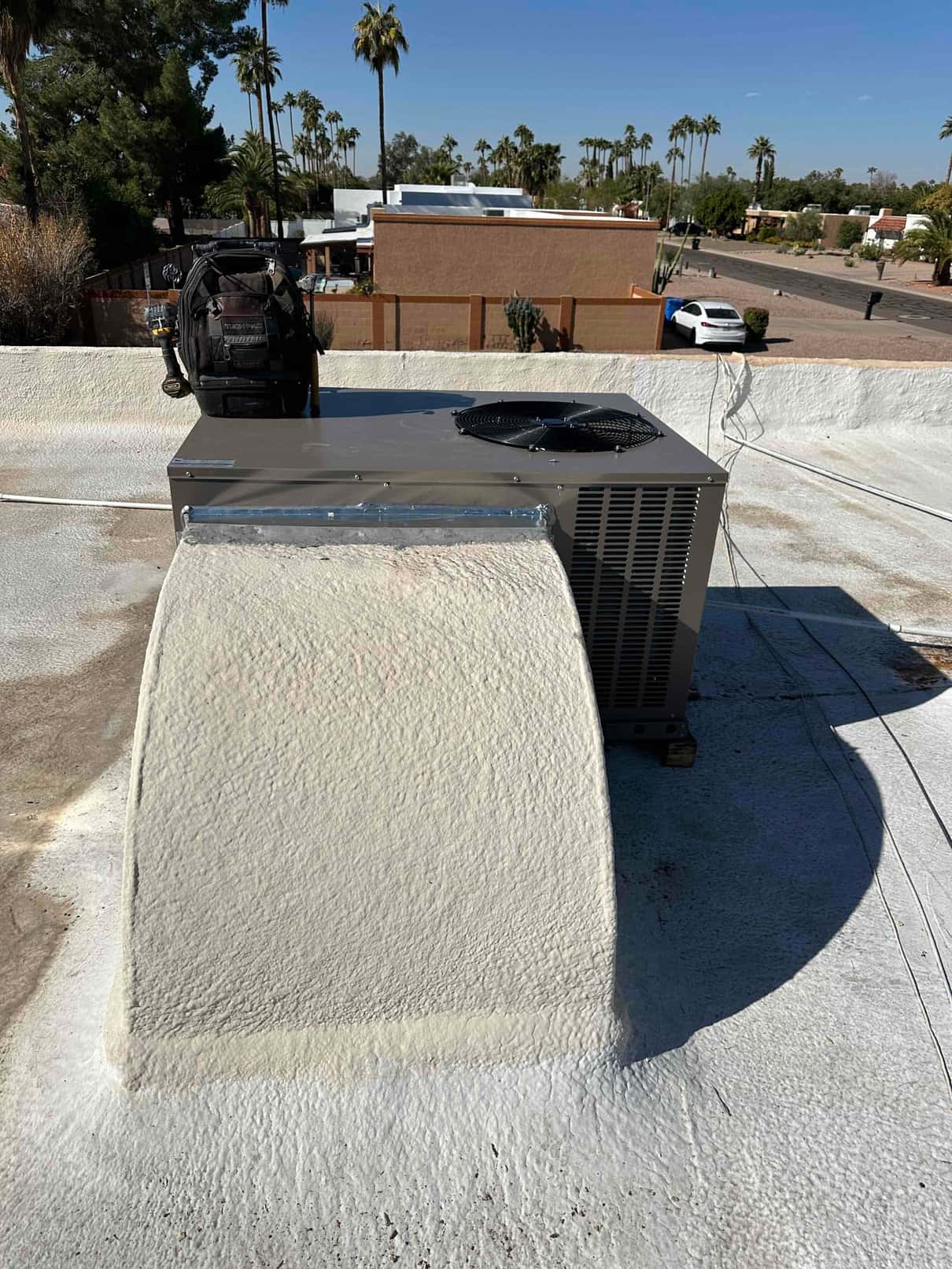 New rooftop package unit set and connected to a sealed curb, with tools staged nearby and wiring routed.