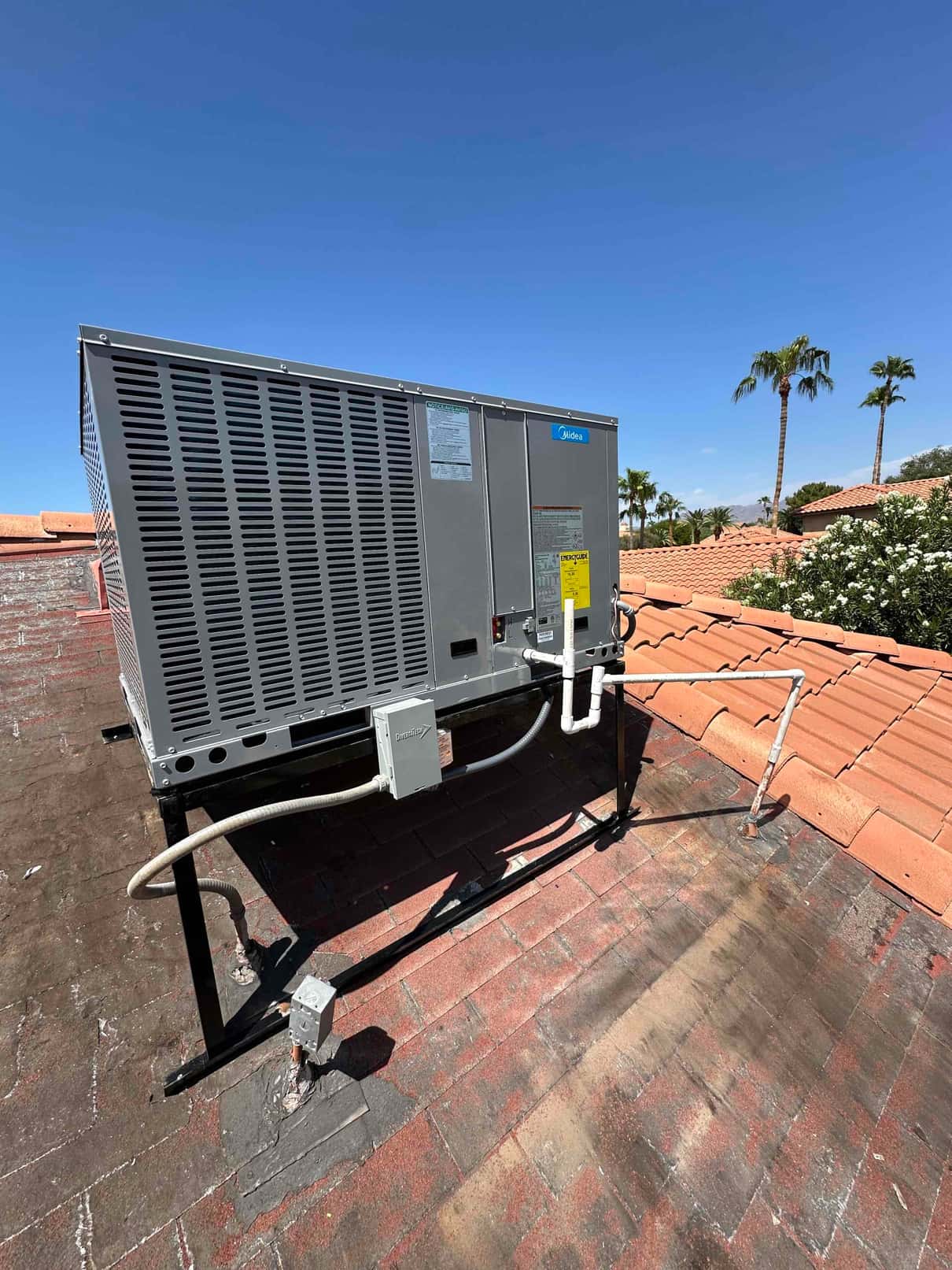 New rooftop package unit set on a metal stand with electrical disconnect, sealed penetrations, and insulated condensate and refrigerant lines.