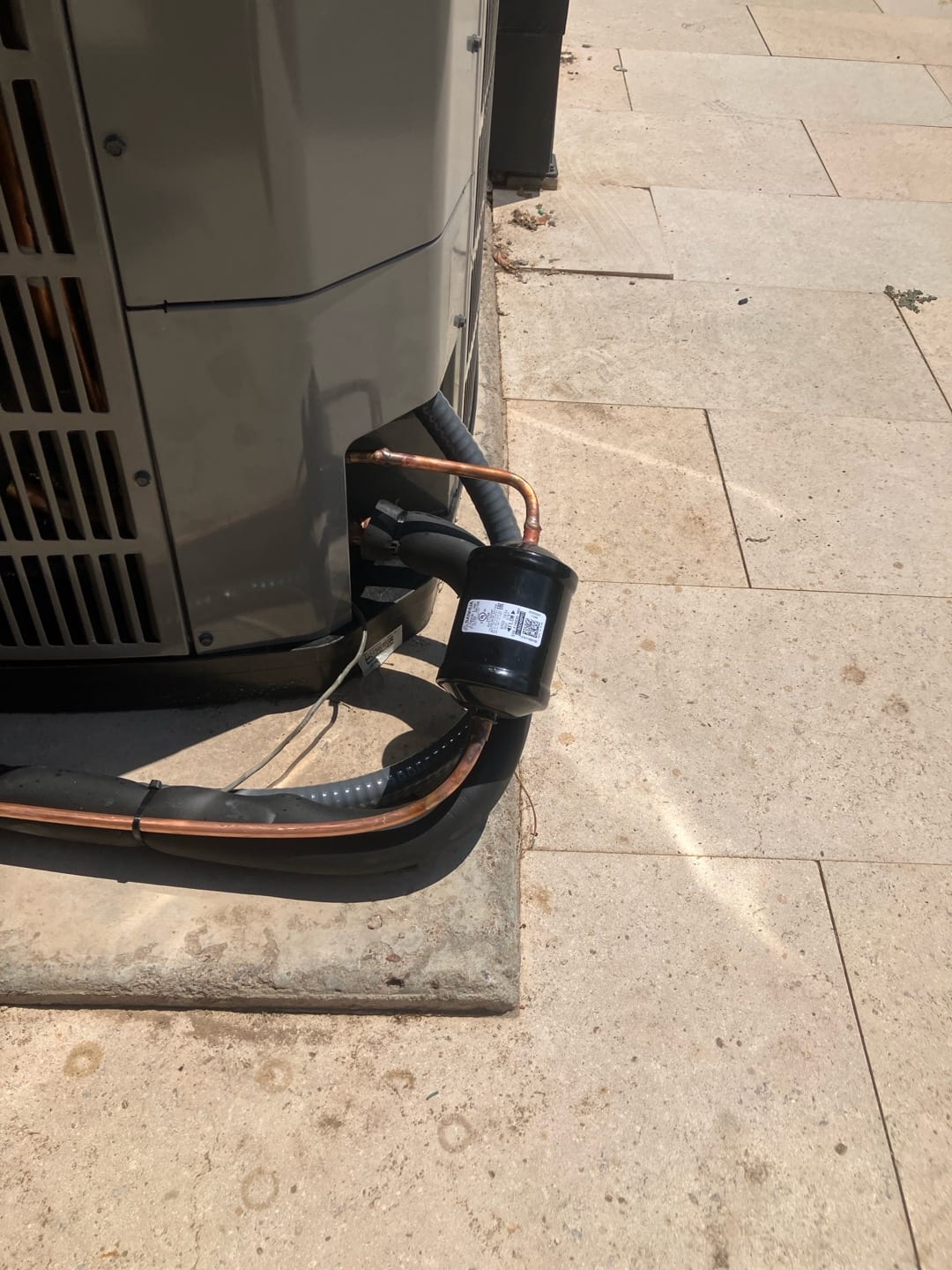 Outdoor condenser with newly brazed refrigerant lines, insulated suction line, and installed filter drier secured along the line set.
