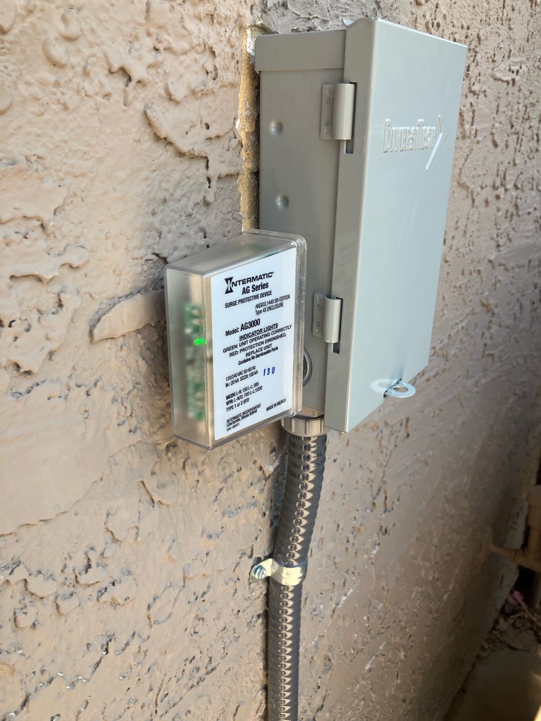 Outdoor HVAC disconnect with installed surge protective device and flexible conduit securely fastened to the exterior wall.