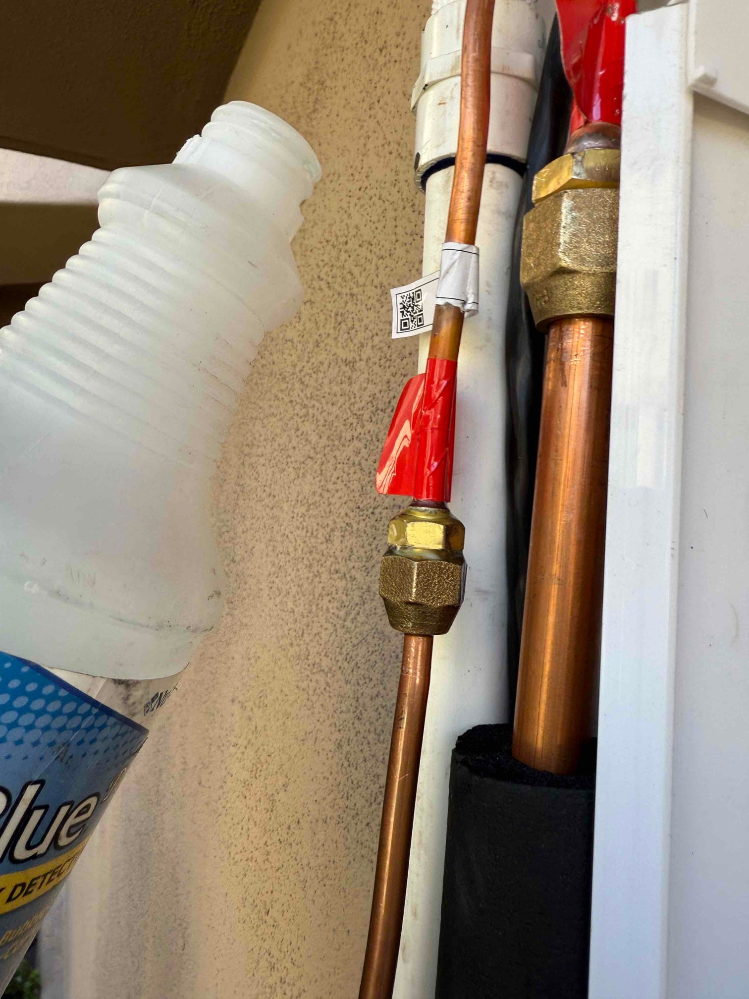 Refrigerant line set connections with insulated suction line and sealed wall penetration during new mini-split installation.