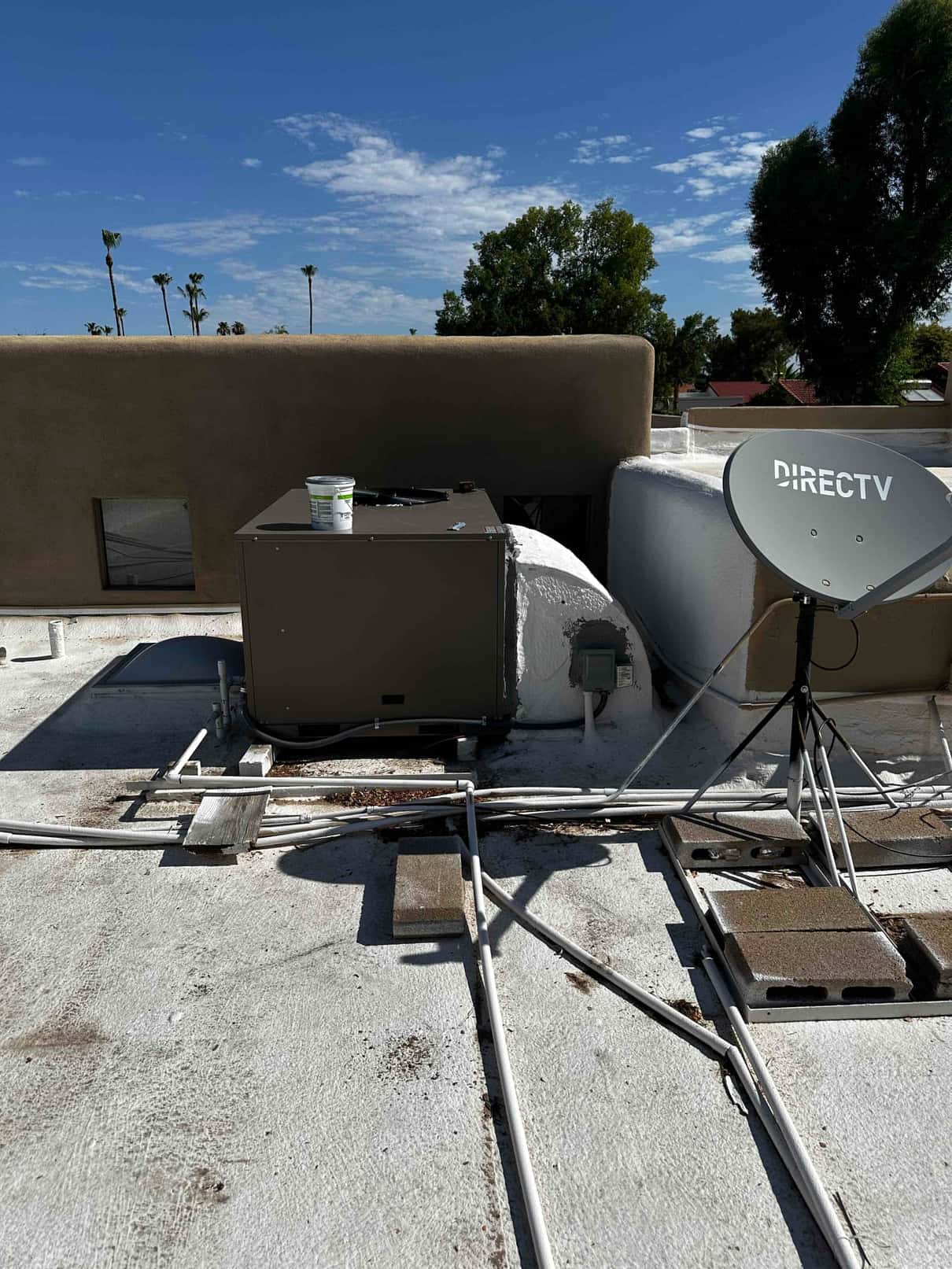 Rooftop packaged HVAC unit installed on a flat roof with connected electrical whip, drain piping, and sealed duct penetration.