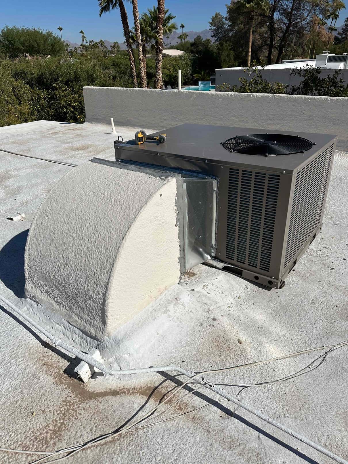 Rooftop packaged HVAC unit newly set on a coated roof, connected to curb and sealed duct transition.