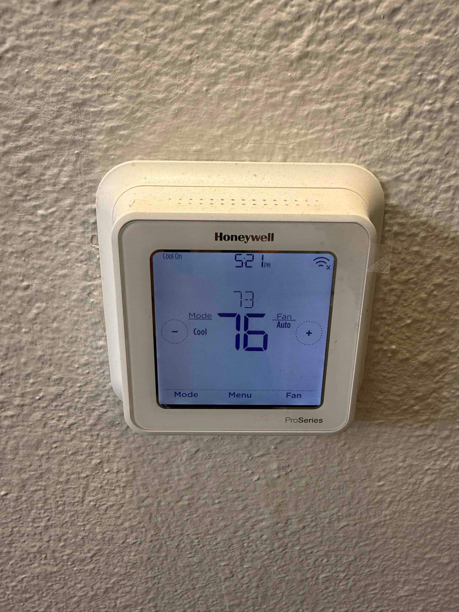 Wall-mounted digital thermostat displays cooling mode with a setpoint of 76 degrees and system status showing Cool On.