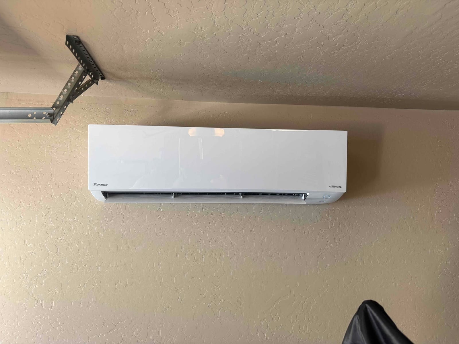 Wall-mounted mini-split indoor unit installed cleanly on a finished wall, with discharge louvers and indicator panel visible.