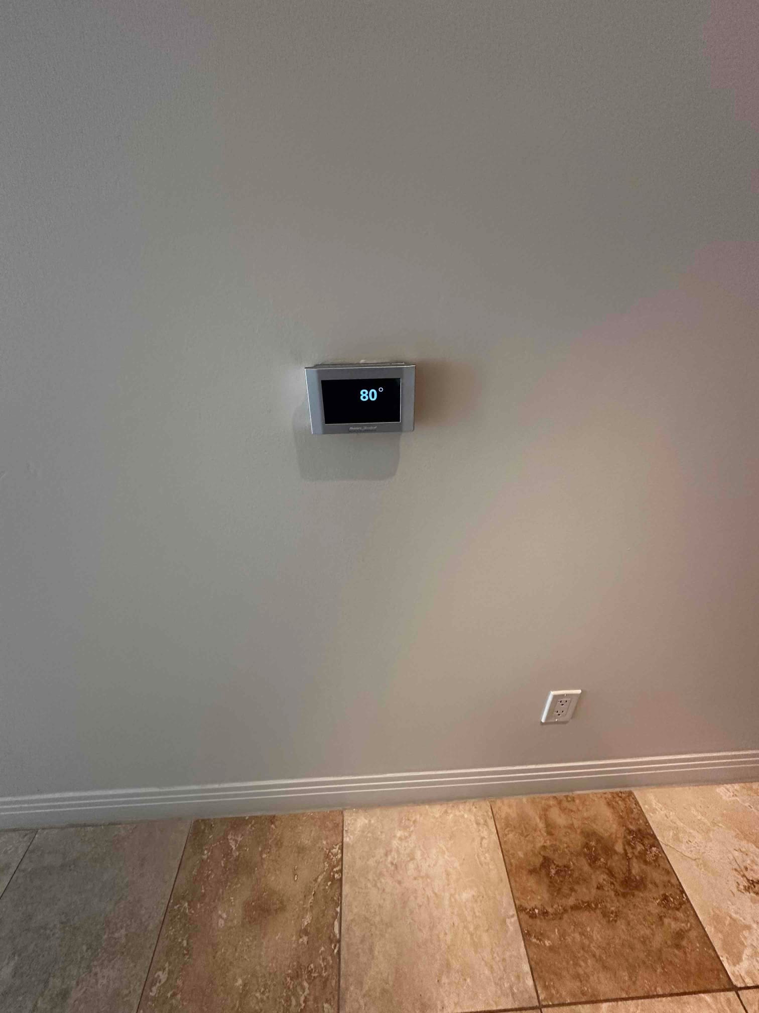 Wall-mounted thermostat displays 80 degrees in a finished interior space, confirming control installation and system interface.