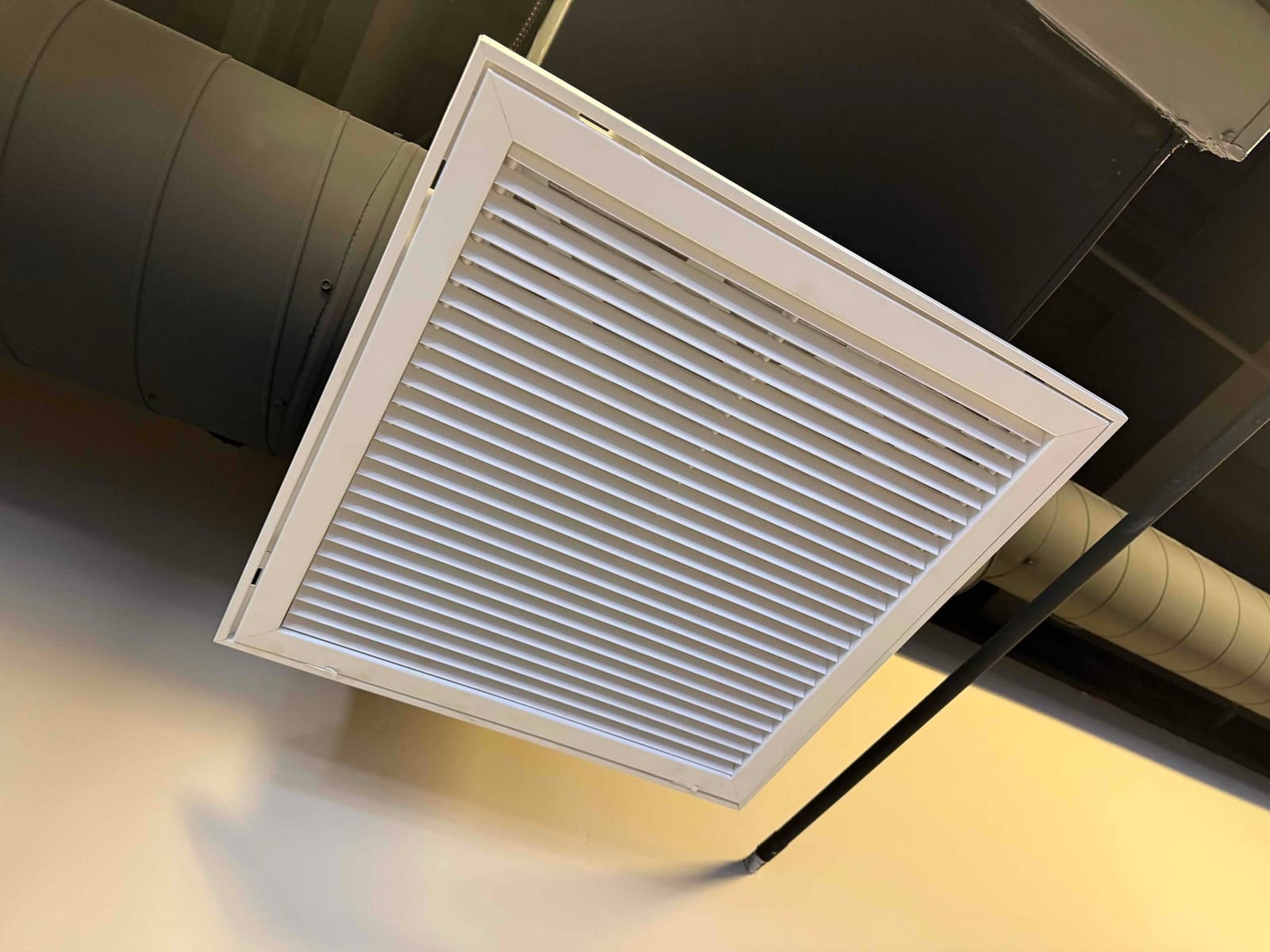 Ceiling-mounted HVAC grille installed on exposed ductwork, showing clean louvers and finished trim in a commercial space.