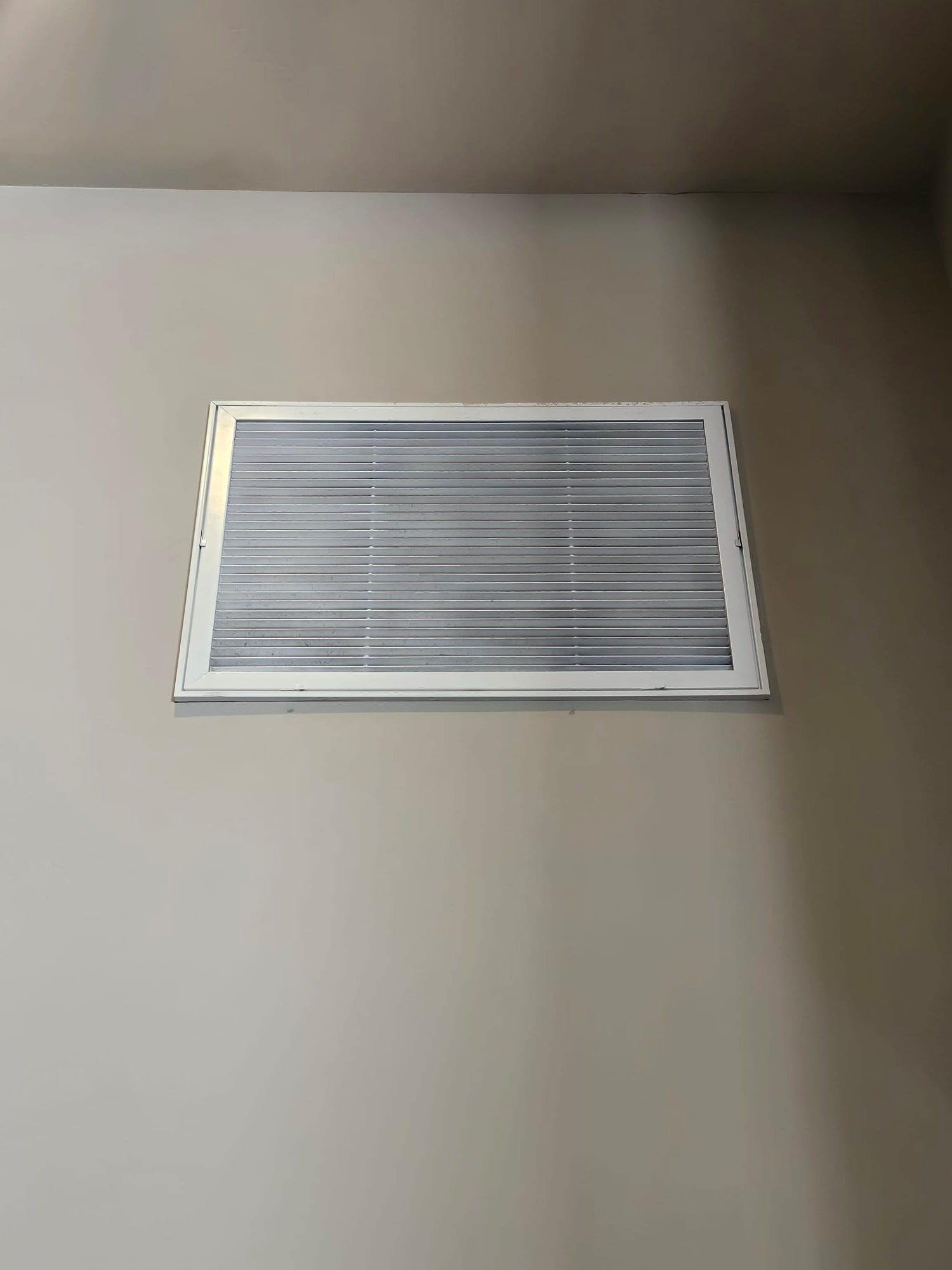Ceiling-mounted return air grille installed flush with the drywall, showing clean frame and horizontal louvers.