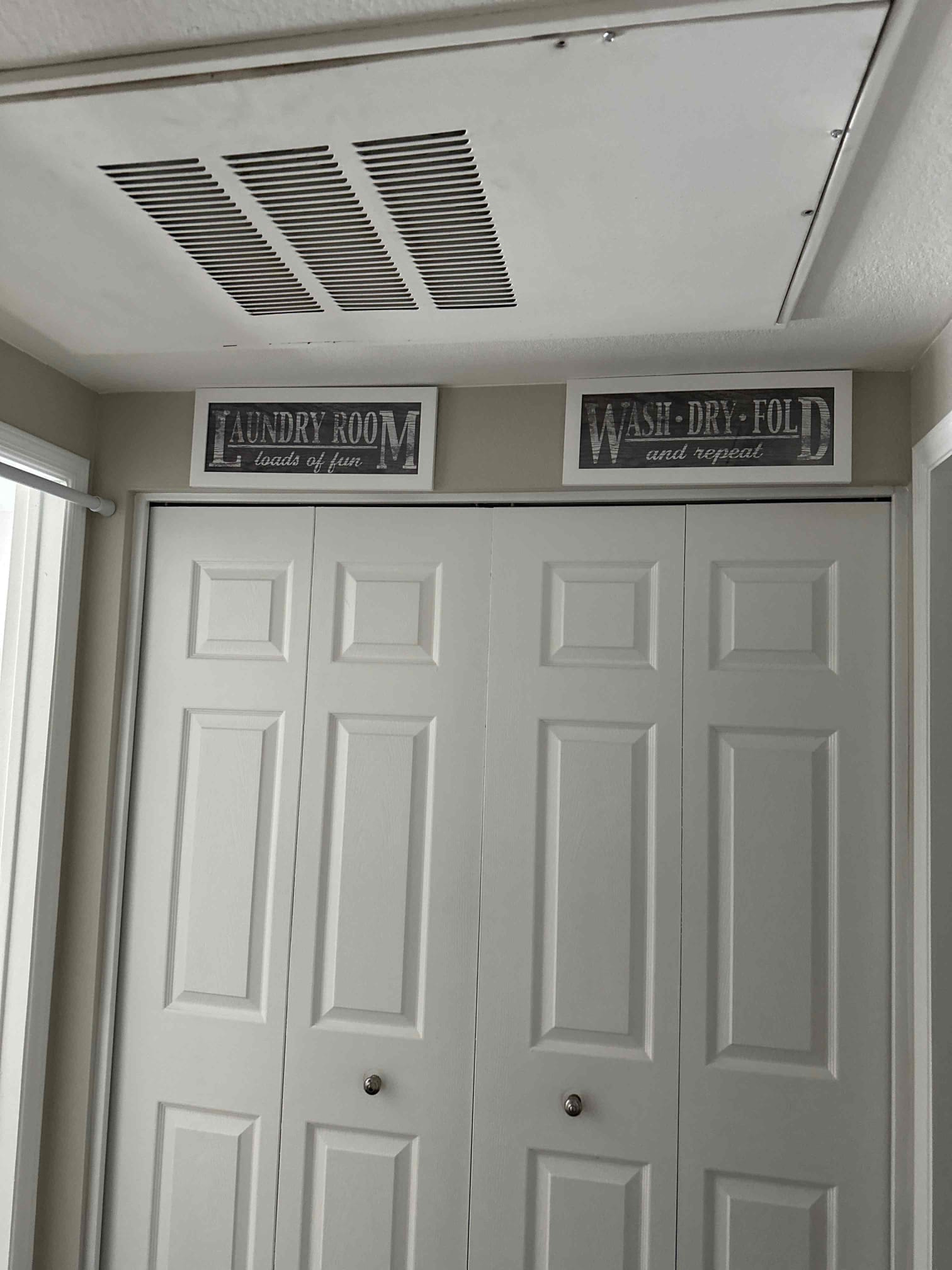 Ceiling return air grille installed above laundry closet, showing clean louvered cover and secure fasteners in a finished hallway ceiling.