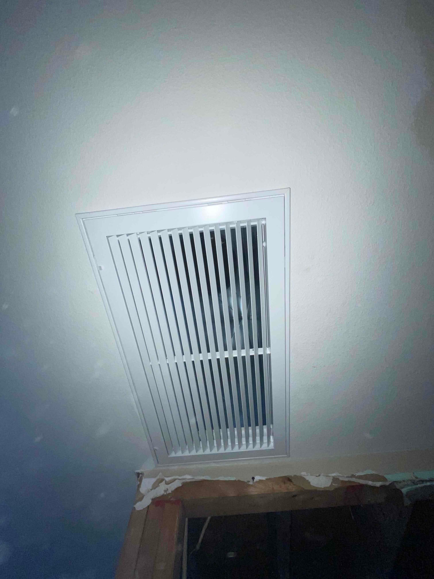 Ceiling return grille installed flush with the drywall near an open framing area, showing finished register and surrounding construction.