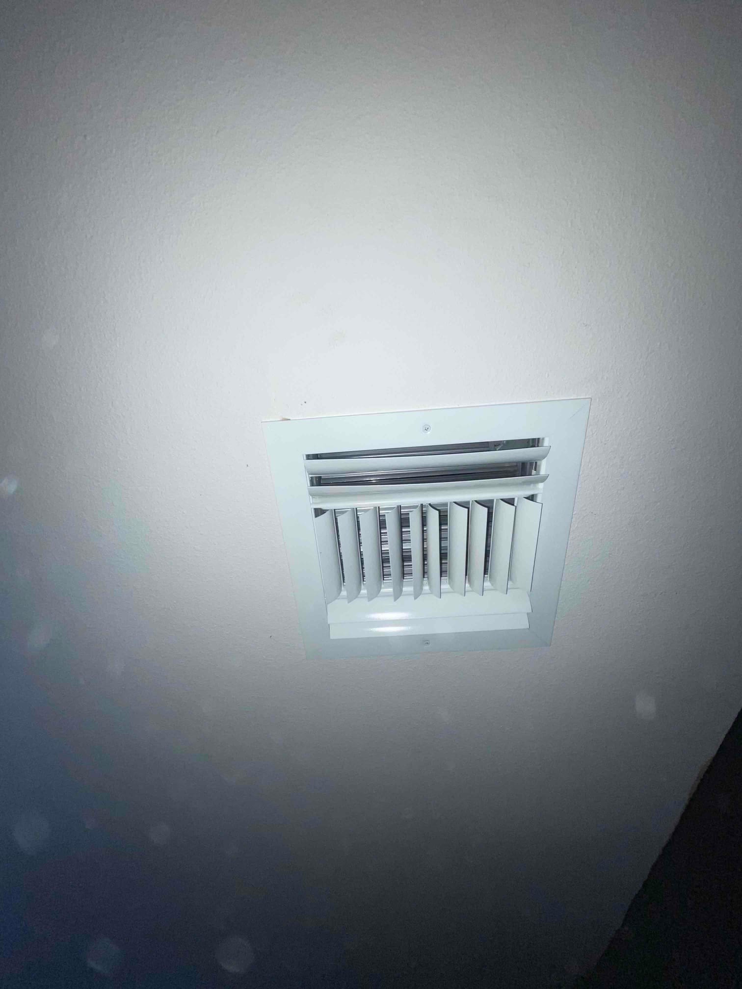 Ceiling supply register installed flush with the drywall, louvers oriented for directional airflow into the room.