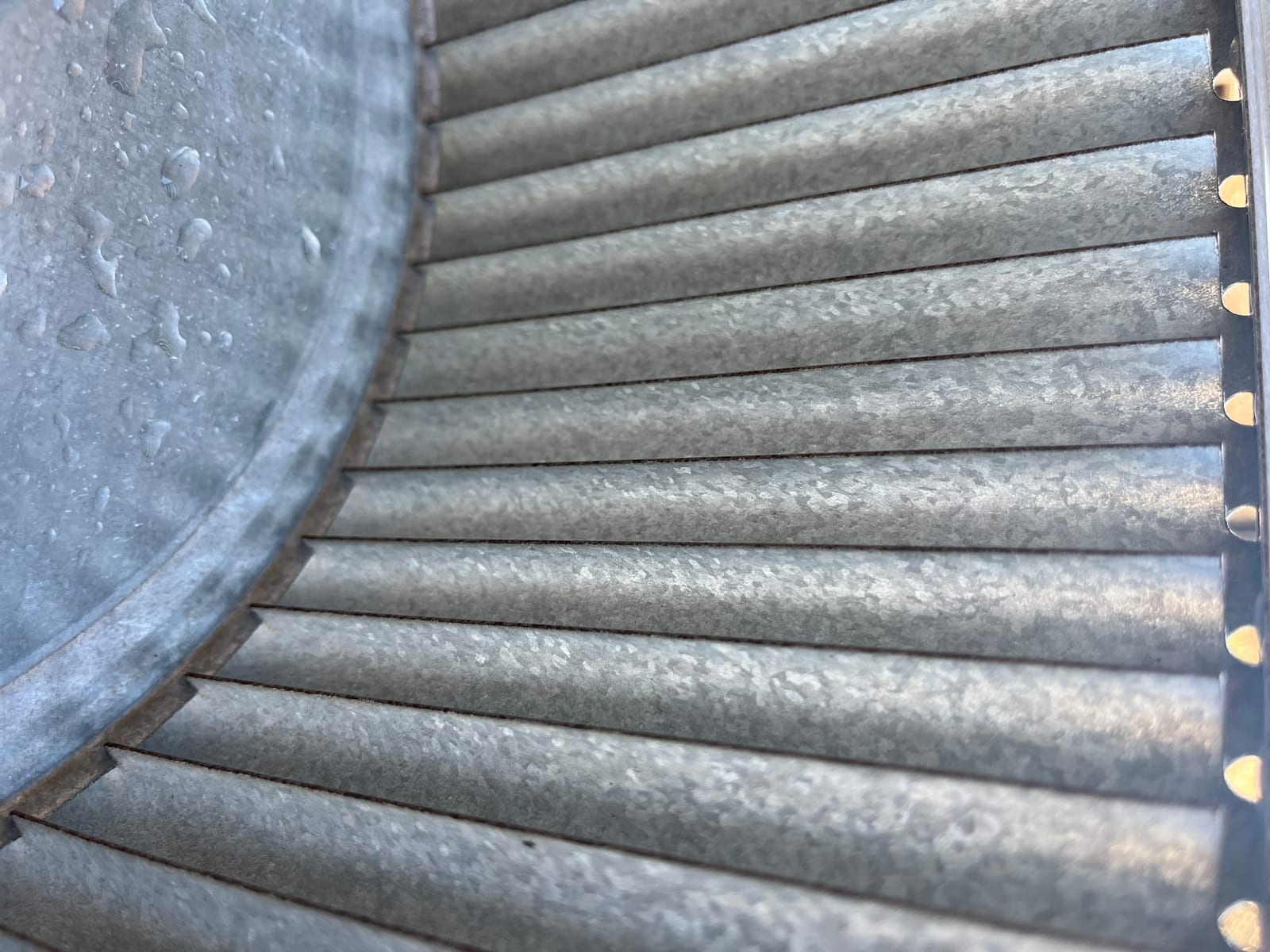 Close-up of a metal blower wheel with dust on the fins, showing the curved blades and circular housing.