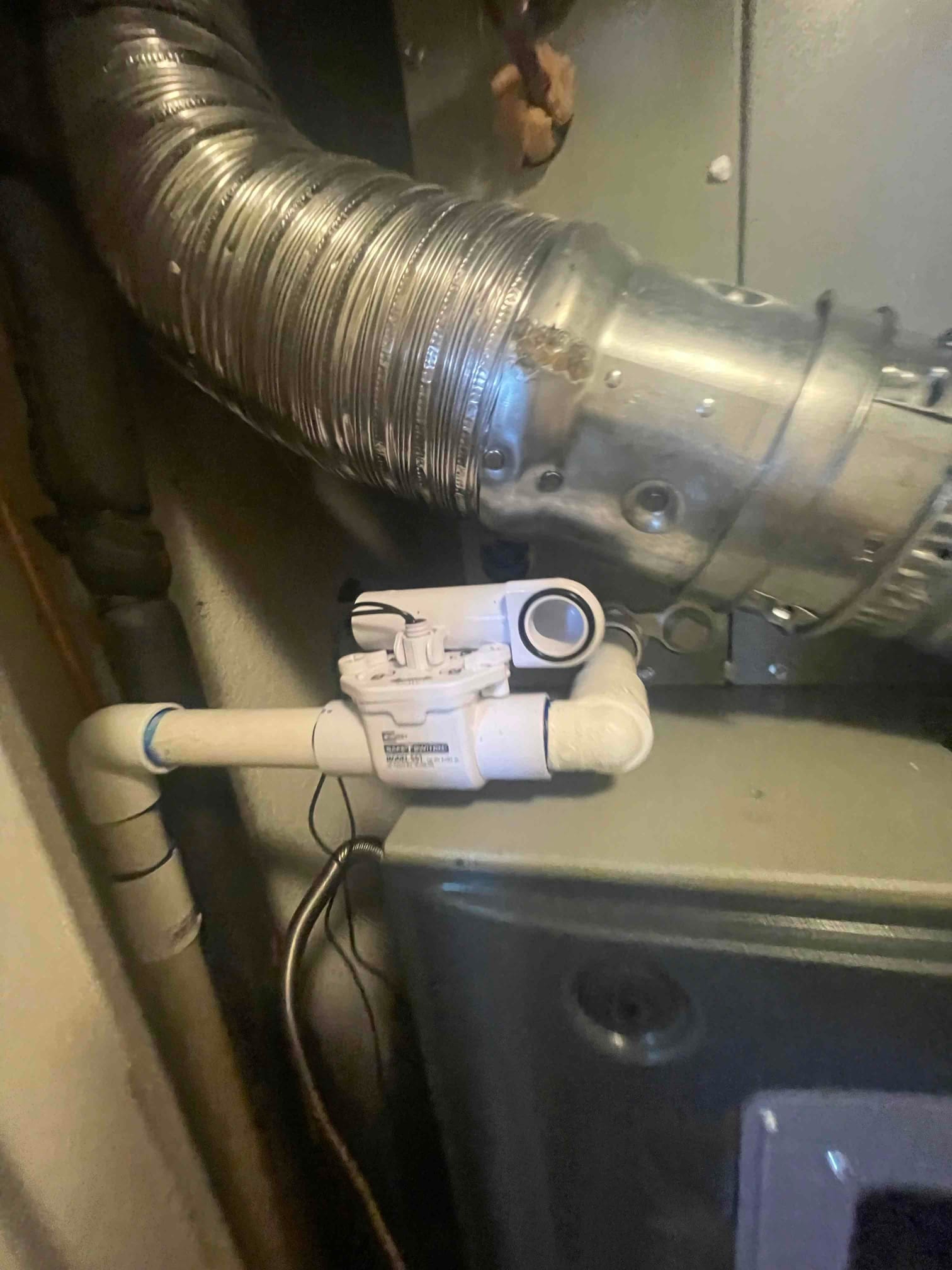 Condensate drain assembly with float safety switch installed on the furnace cabinet beside the flue vent connector.
