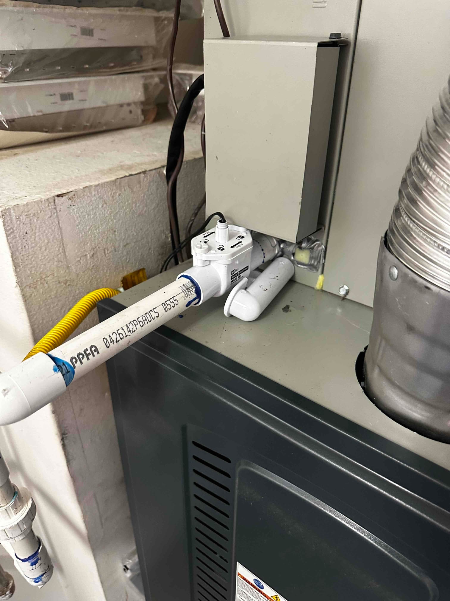 Condensate drain with float safety switch installed at the furnace, adjacent to gas flex connector and vent duct.