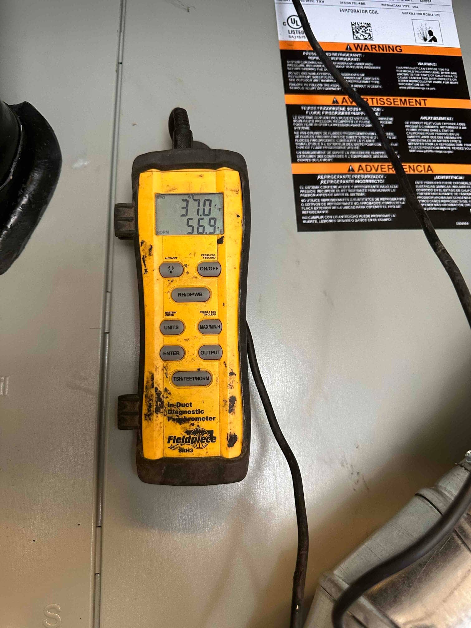 Digital in-duct thermometer displays 56.9 degrees Fahrenheit, documenting supply air temperature during system commissioning.